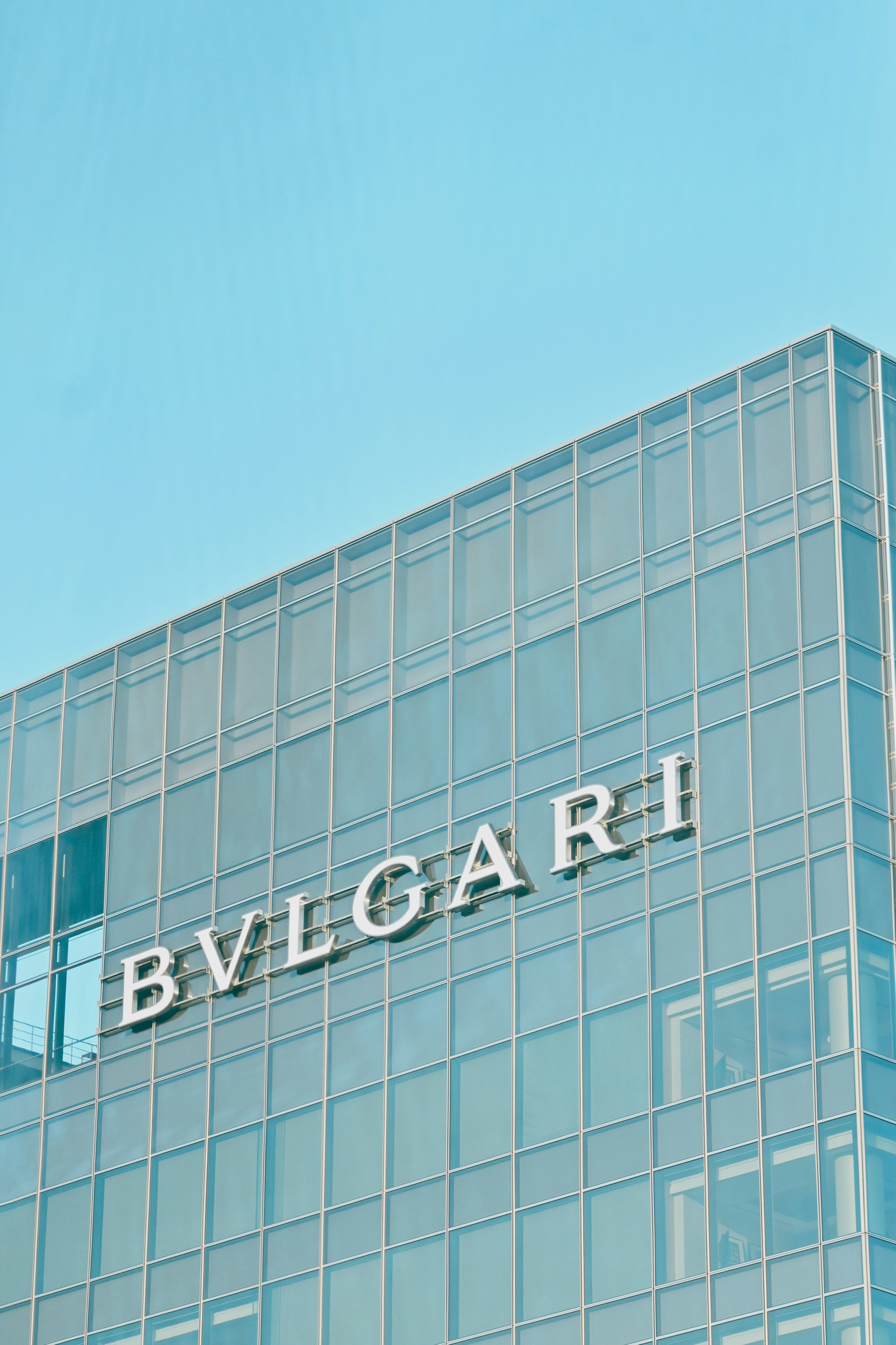 맑은 파란 하늘 아래 Bvlgari 로고가 있는 유리 건물