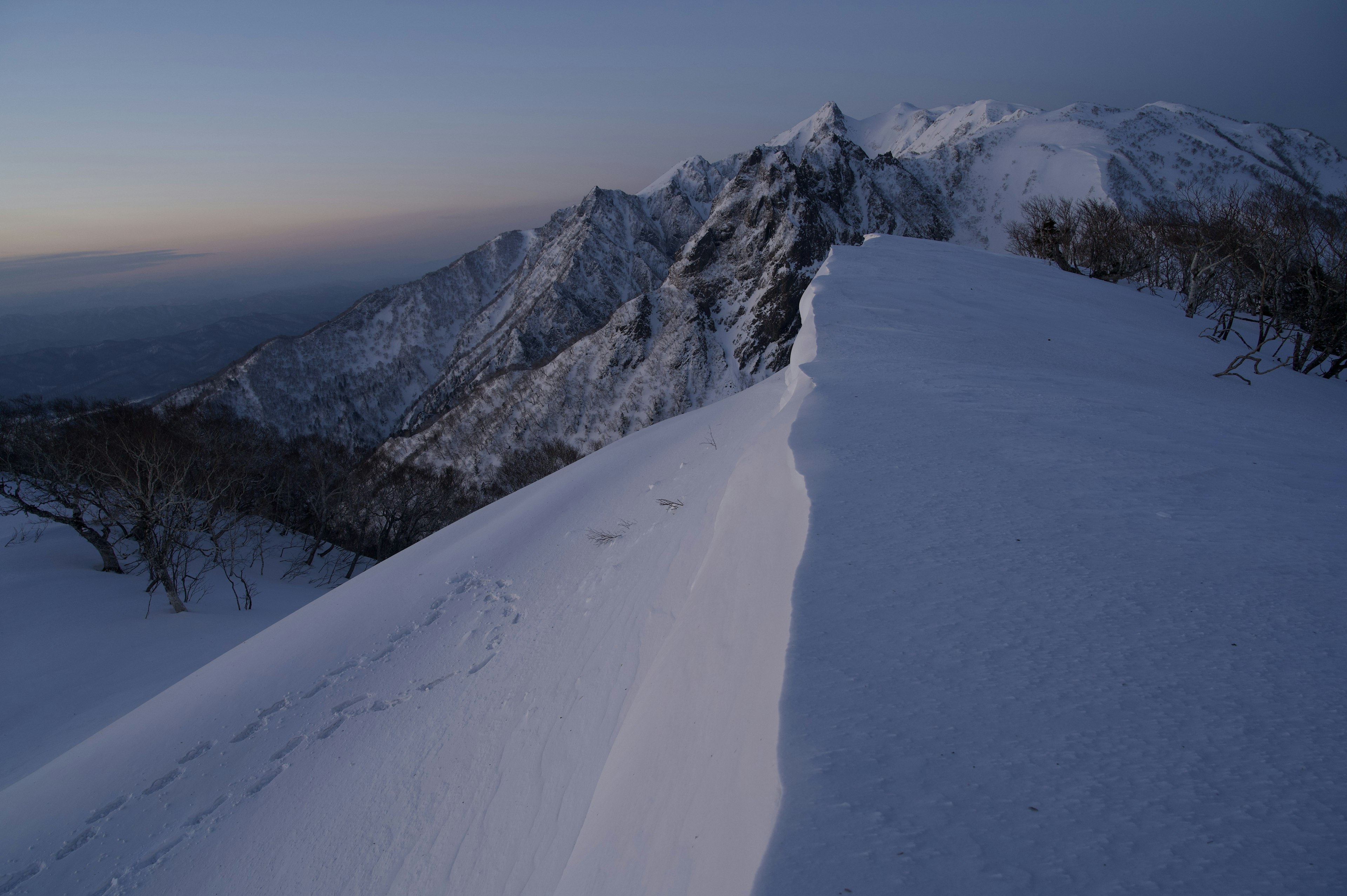 Paisaje montañoso cubierto de nieve con cielo crepuscular