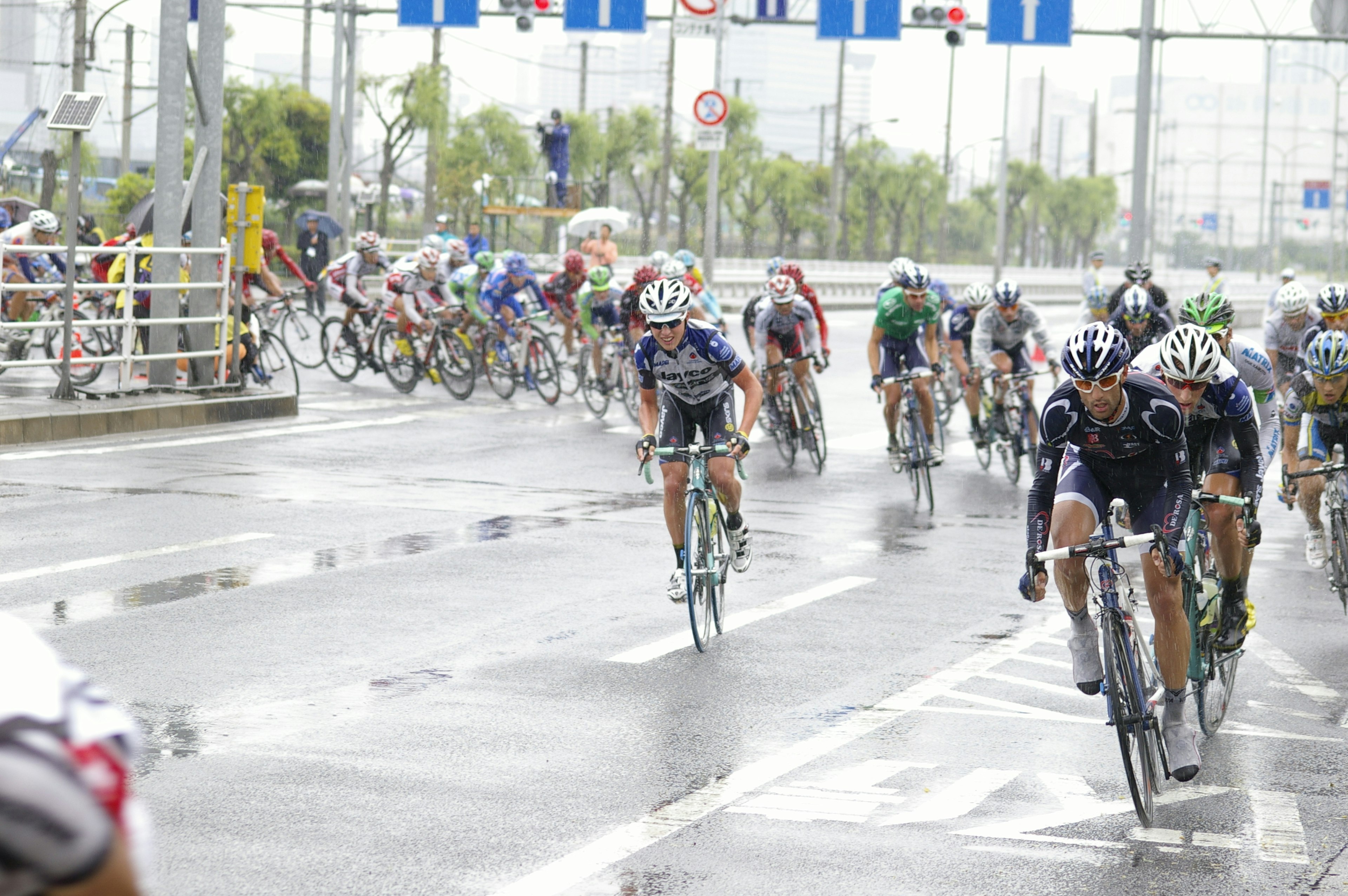 Ciclistas compitiendo bajo la lluvia en una carretera mojada