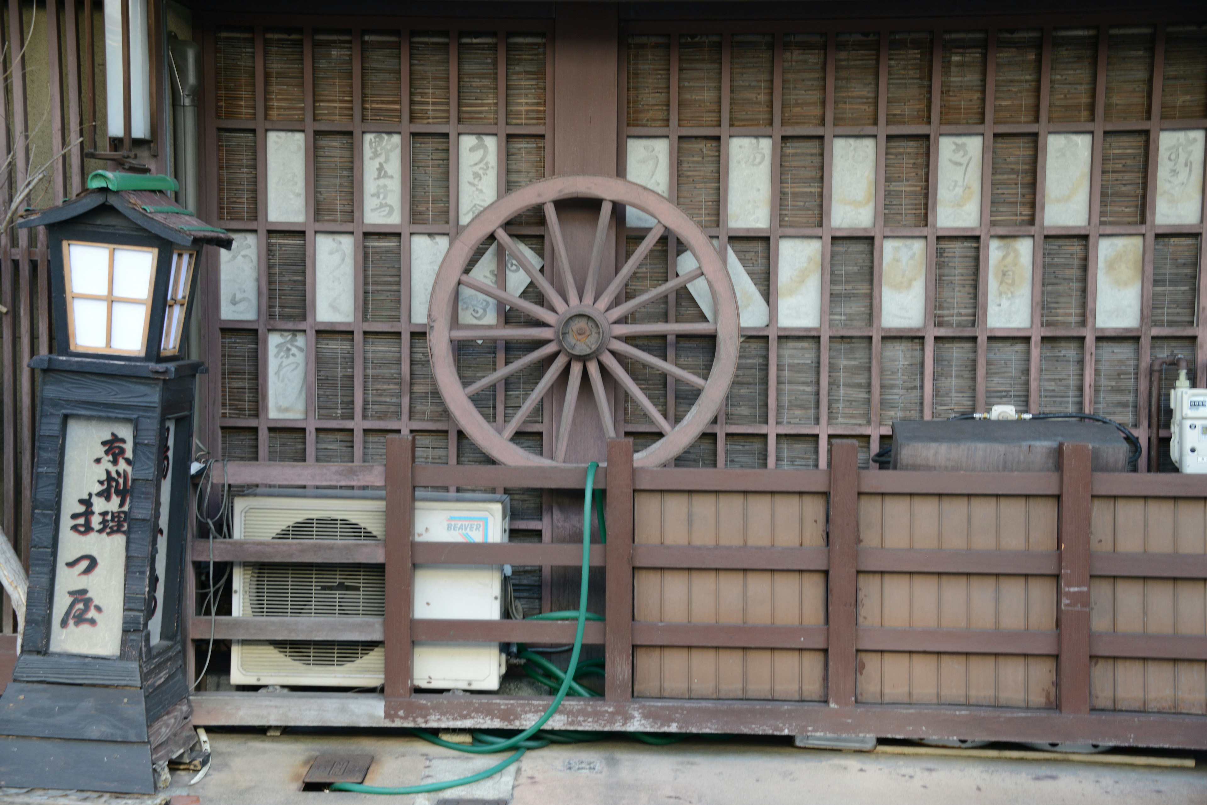 Exterior of a traditional Japanese building featuring a wooden wheel and lantern