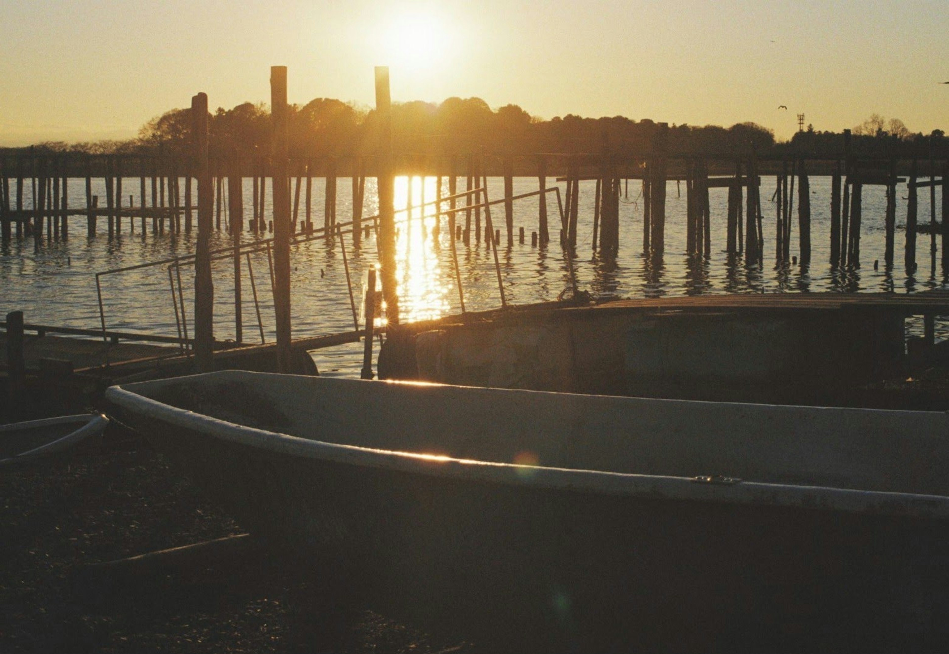 Boot und Pier-Silhouette gegen den Sonnenuntergang, der sich im Wasser spiegelt