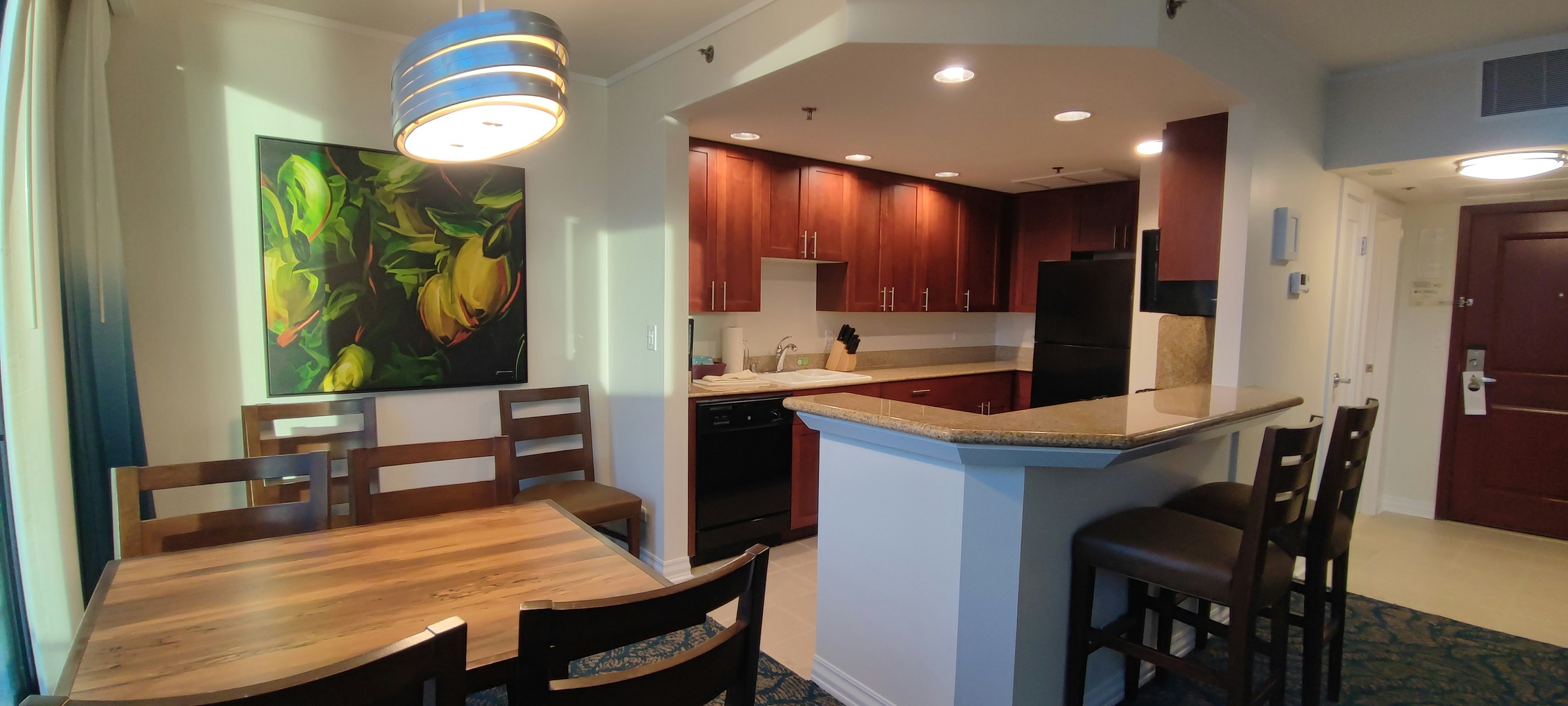 Modern kitchen and dining area interior image Wooden table and chairs Lighting fixture and colorful artwork