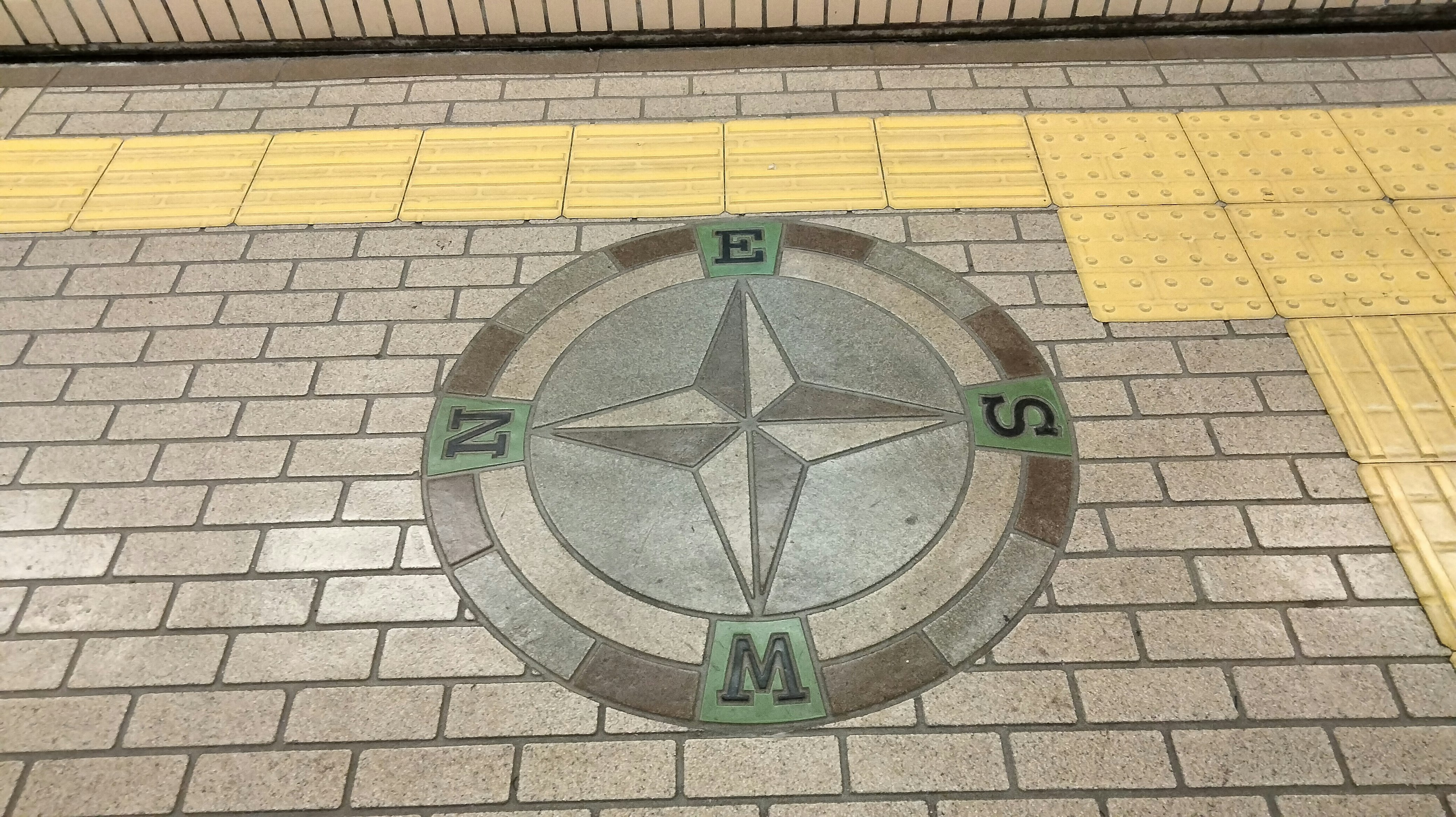 Mosaico de diseño de brújula en el suelo de la estación