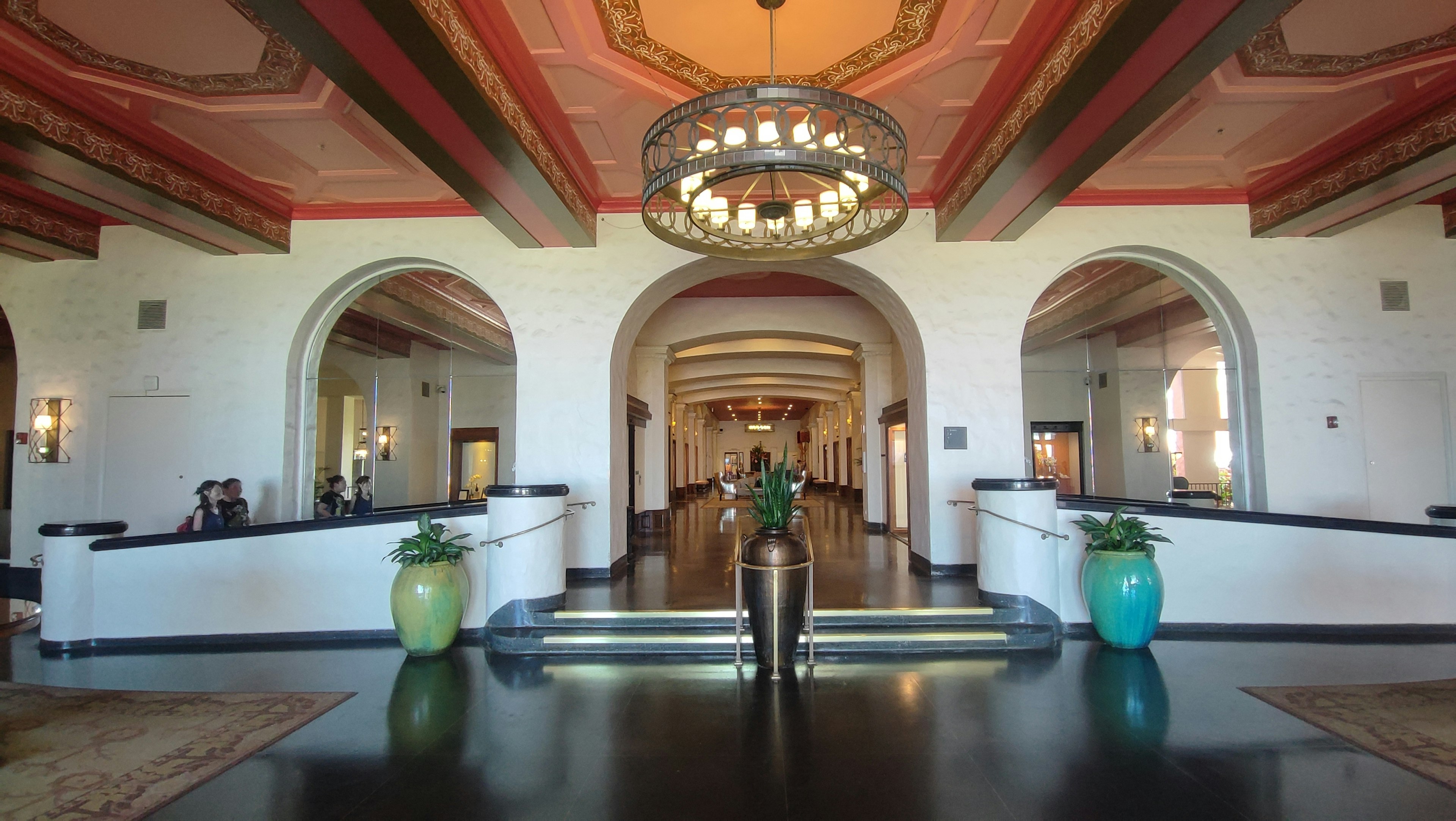 Luxurious lobby with a person standing in the center and decorative chandelier