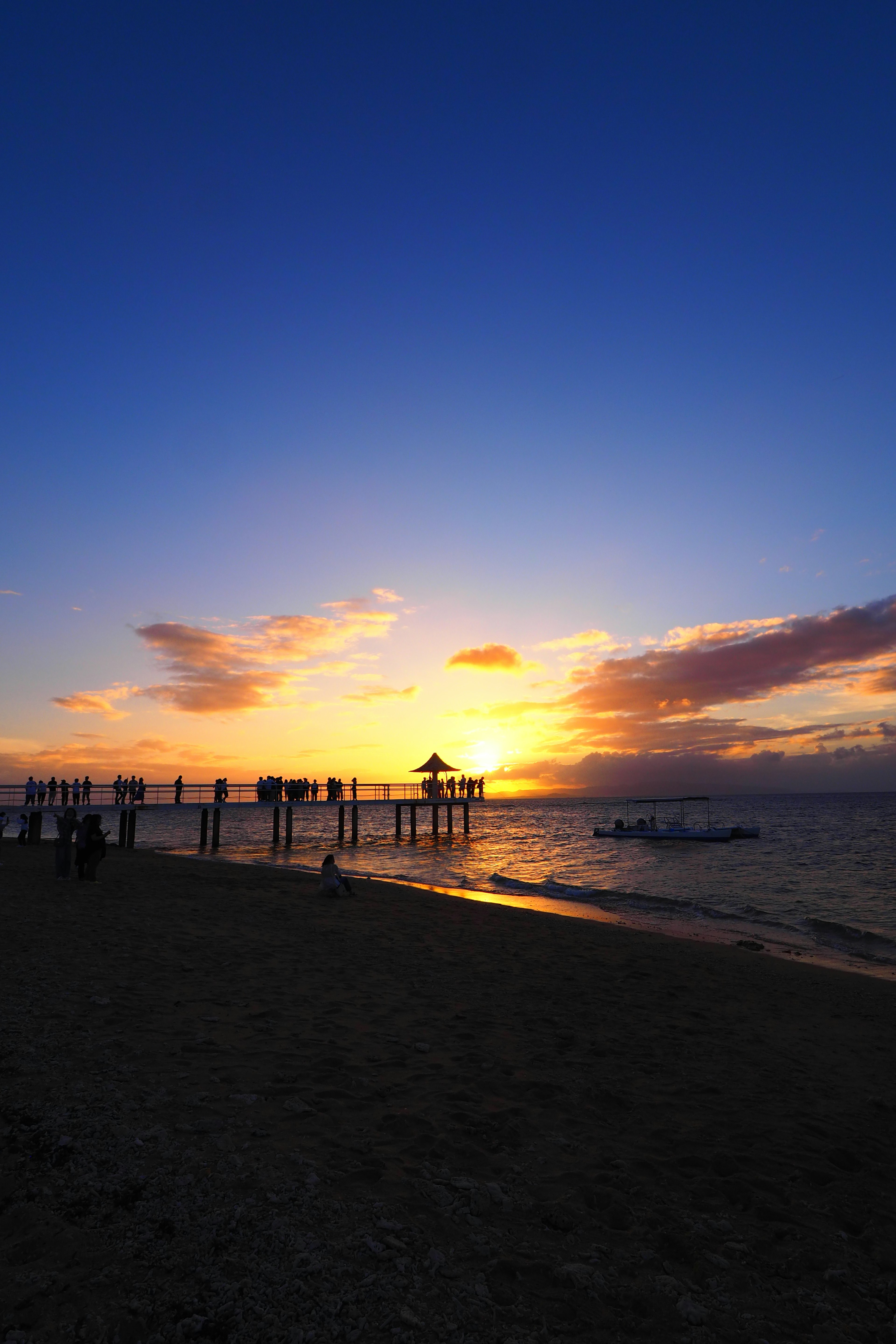 Vista de playa escénica con la silueta de un muelle al atardecer