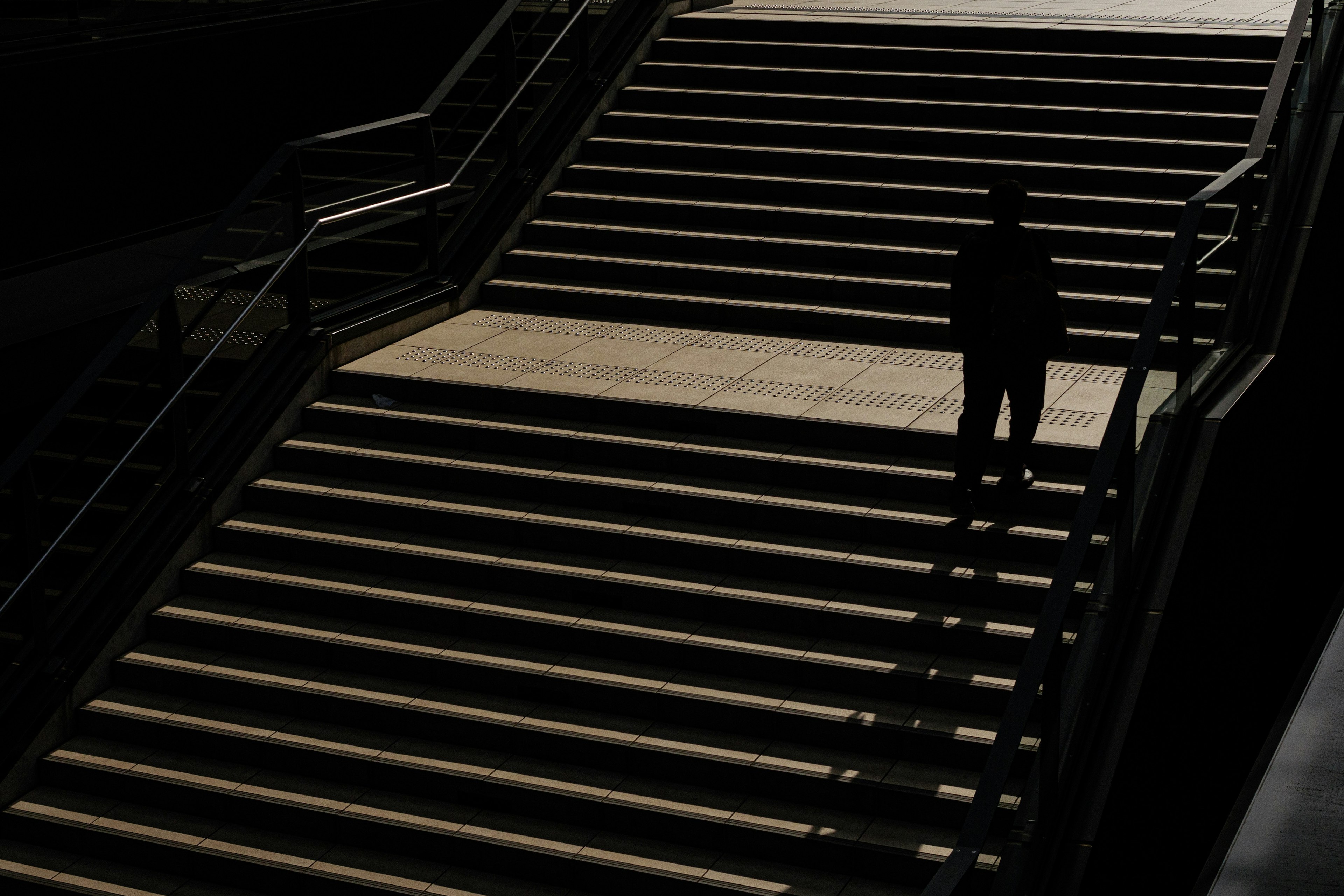 Silhouette of a person on a staircase with bright wooden steps