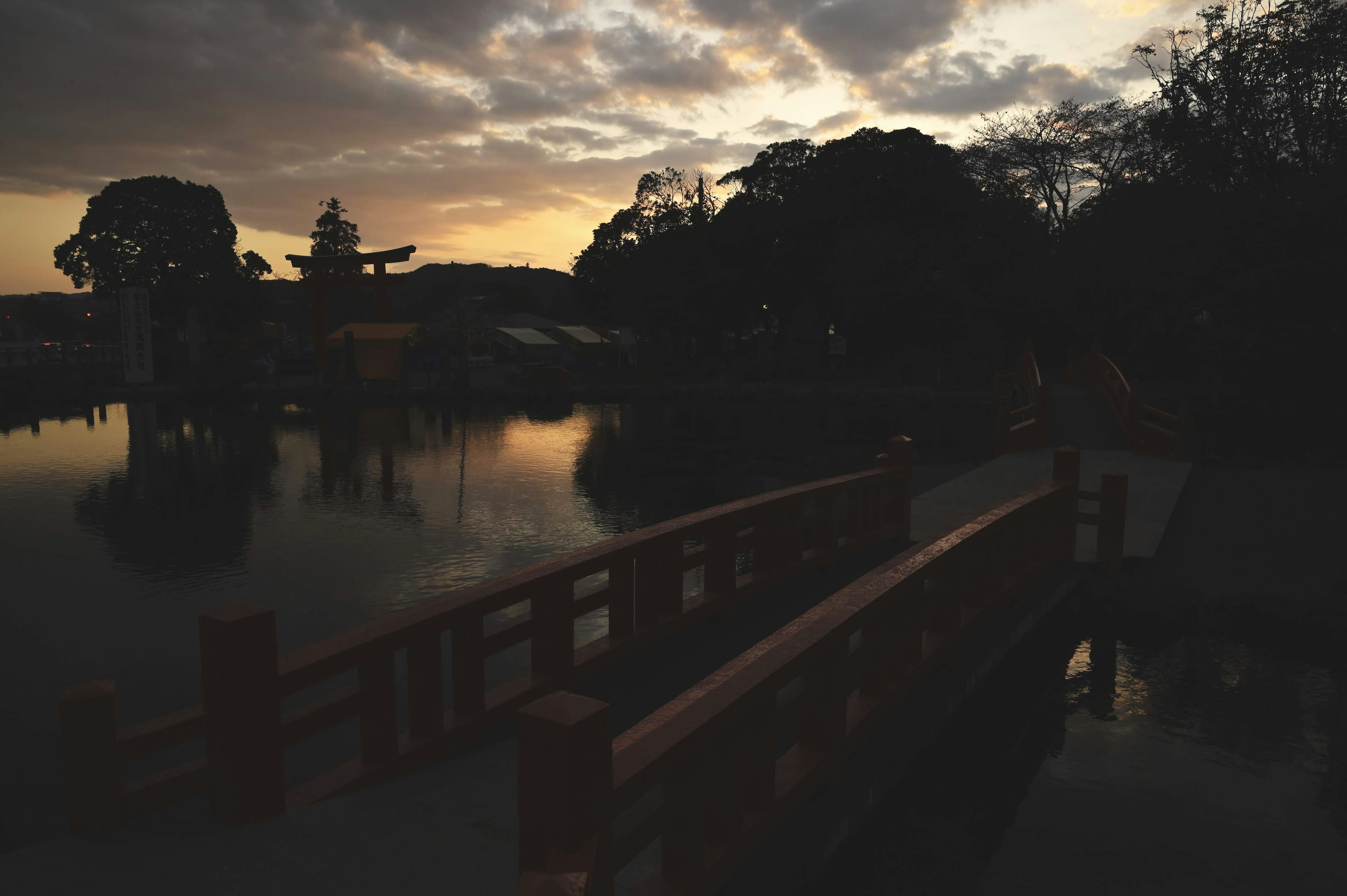 Pont rouge sur un étang au crépuscule avec des arbres en silhouette