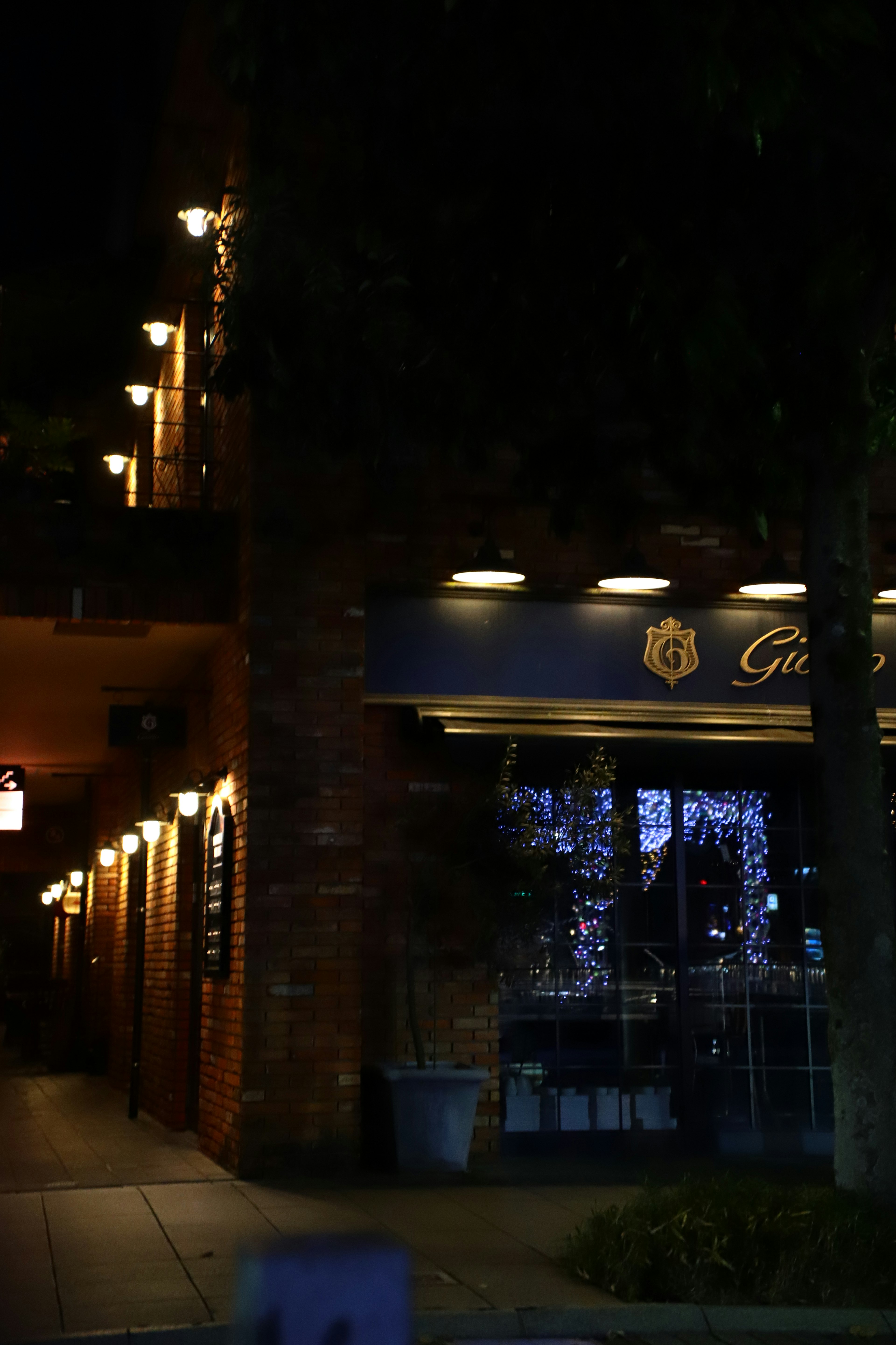 Extérieur d'un restaurant la nuit avec des lumières scintillantes et une ambiance urbaine