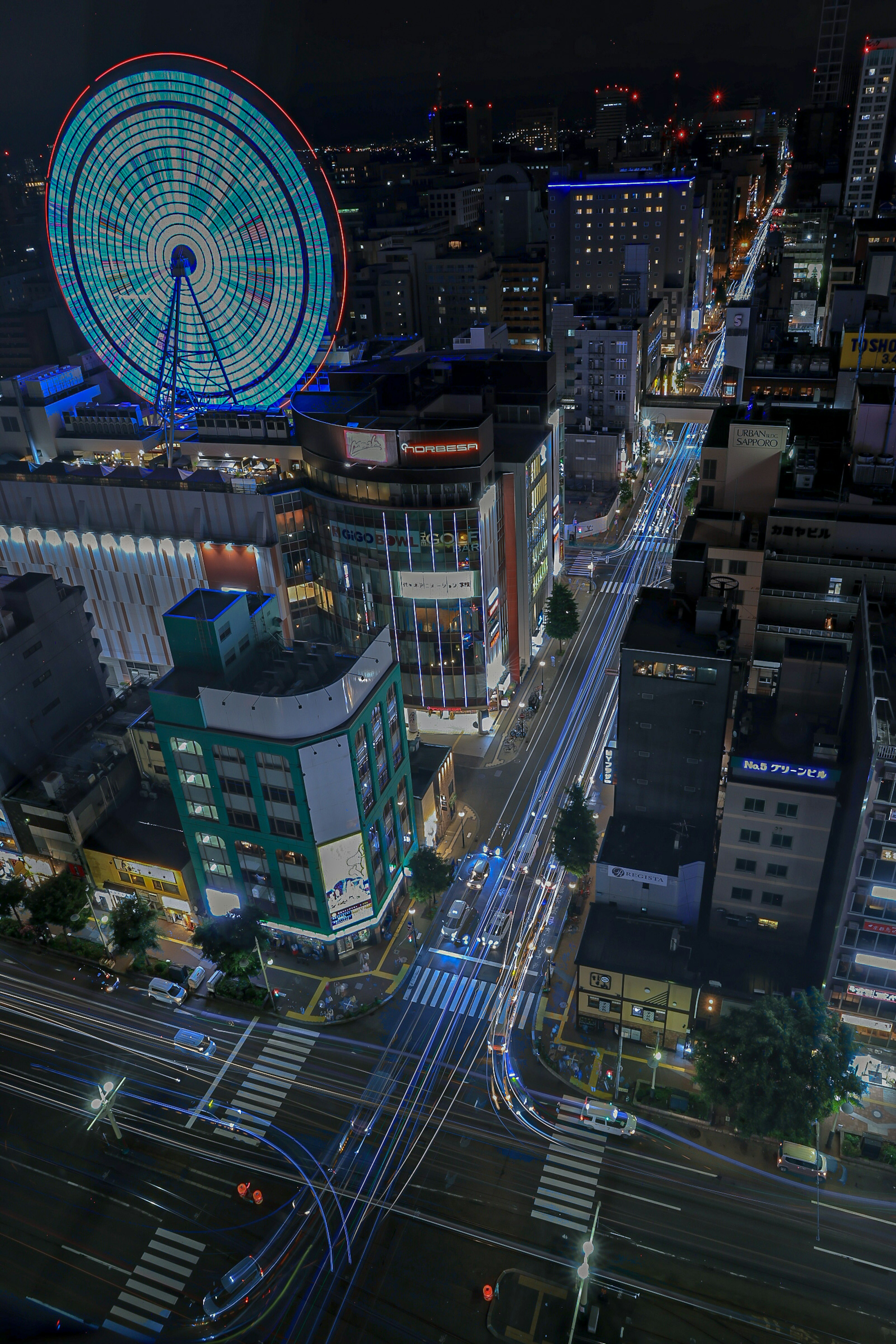 Night view of a bustling intersection with skyscrapers and a ferris wheel