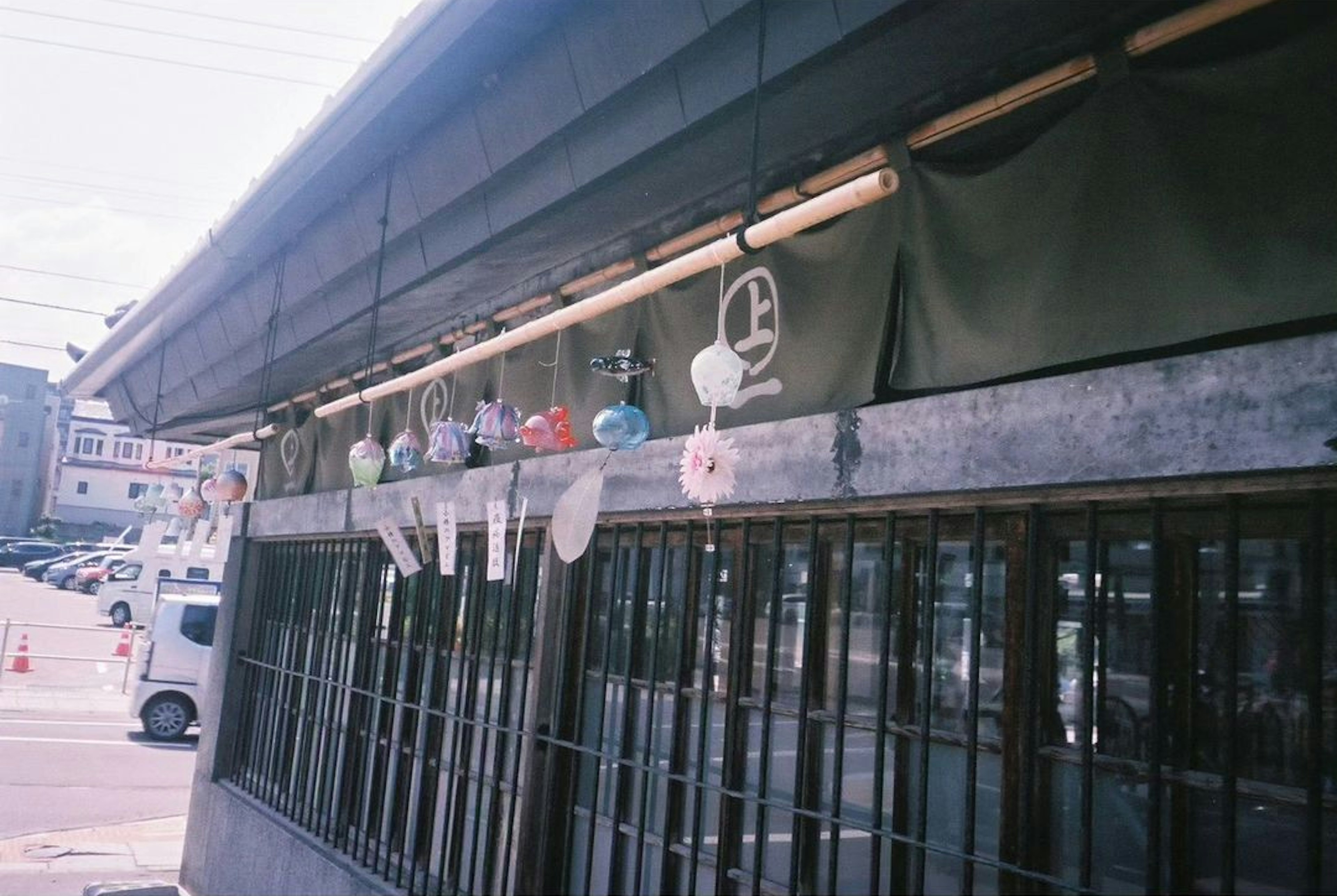 Colorful wind chimes hanging outside a building with a green curtain