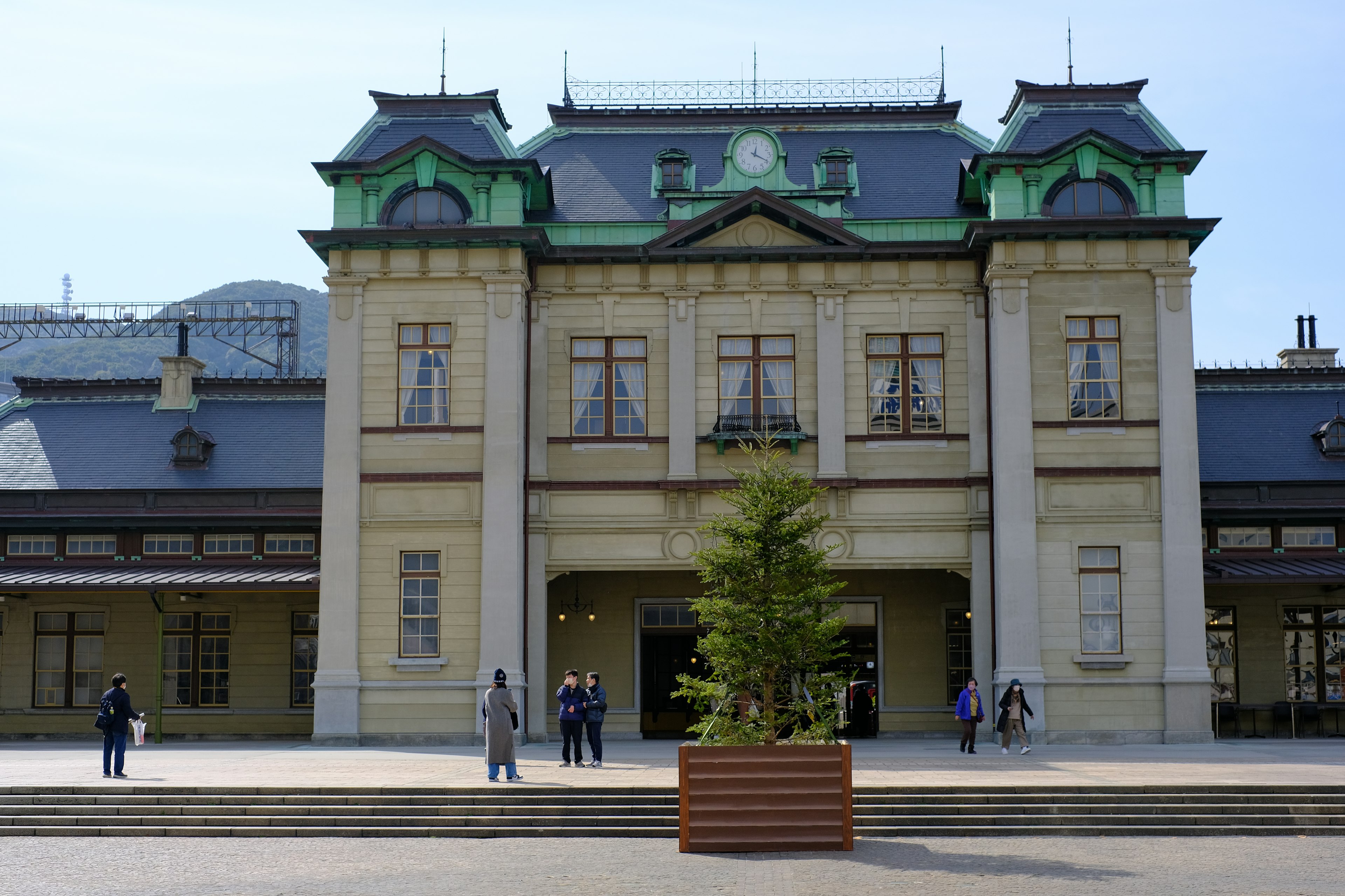 Historischer Bahnhof mit grünem Dach und Holzpflanzkübel davor