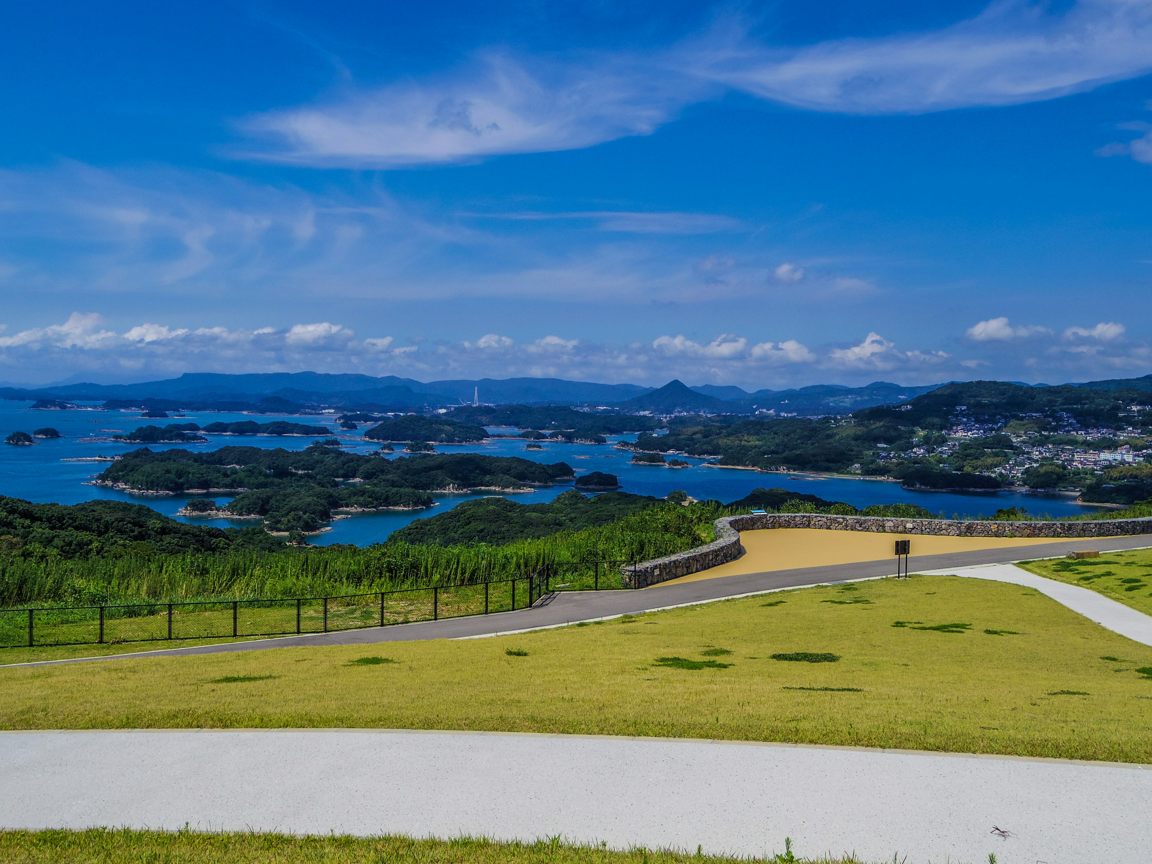 Scenic view of blue sea and green hills under a clear blue sky