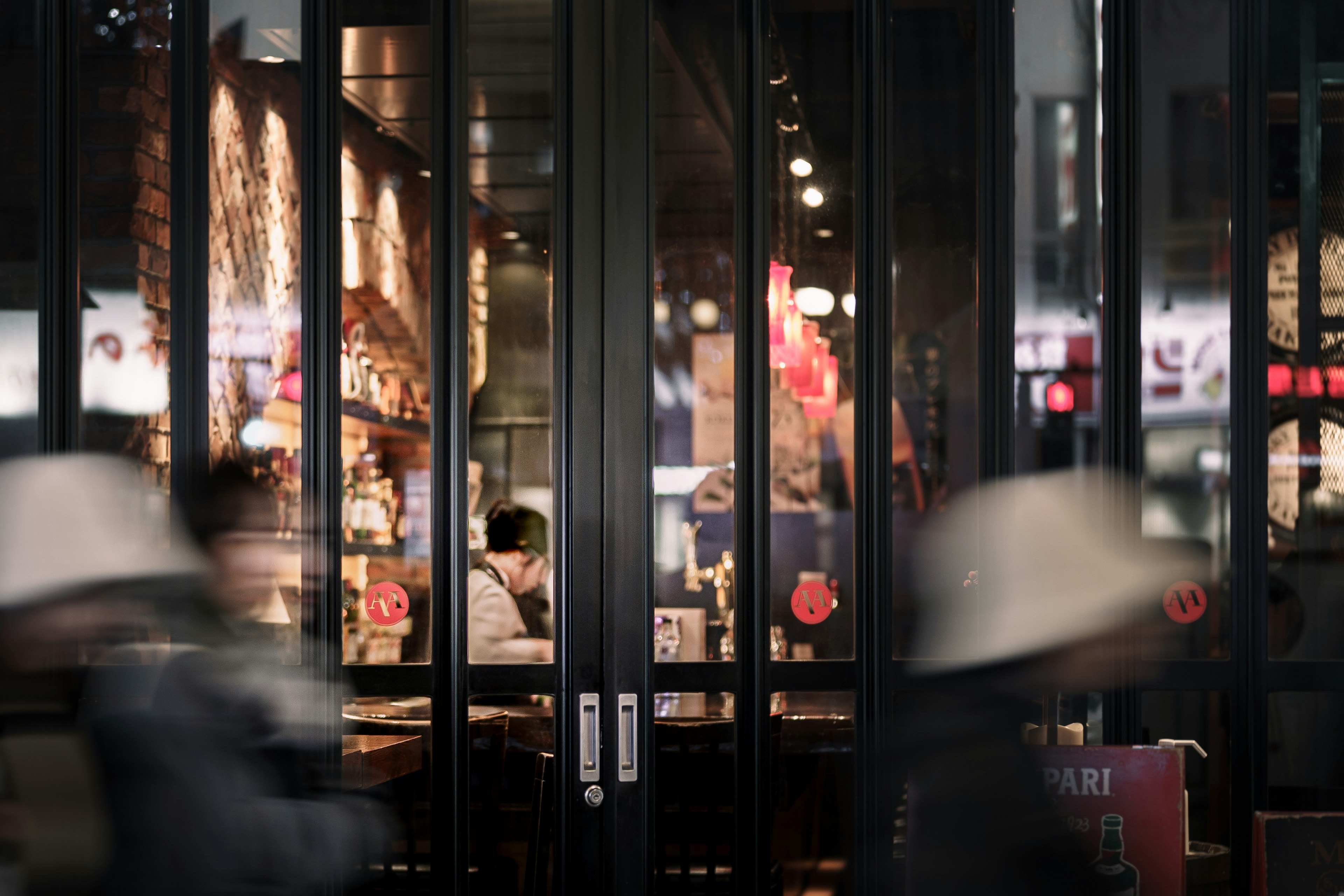 People walking past a restaurant entrance at night in a city