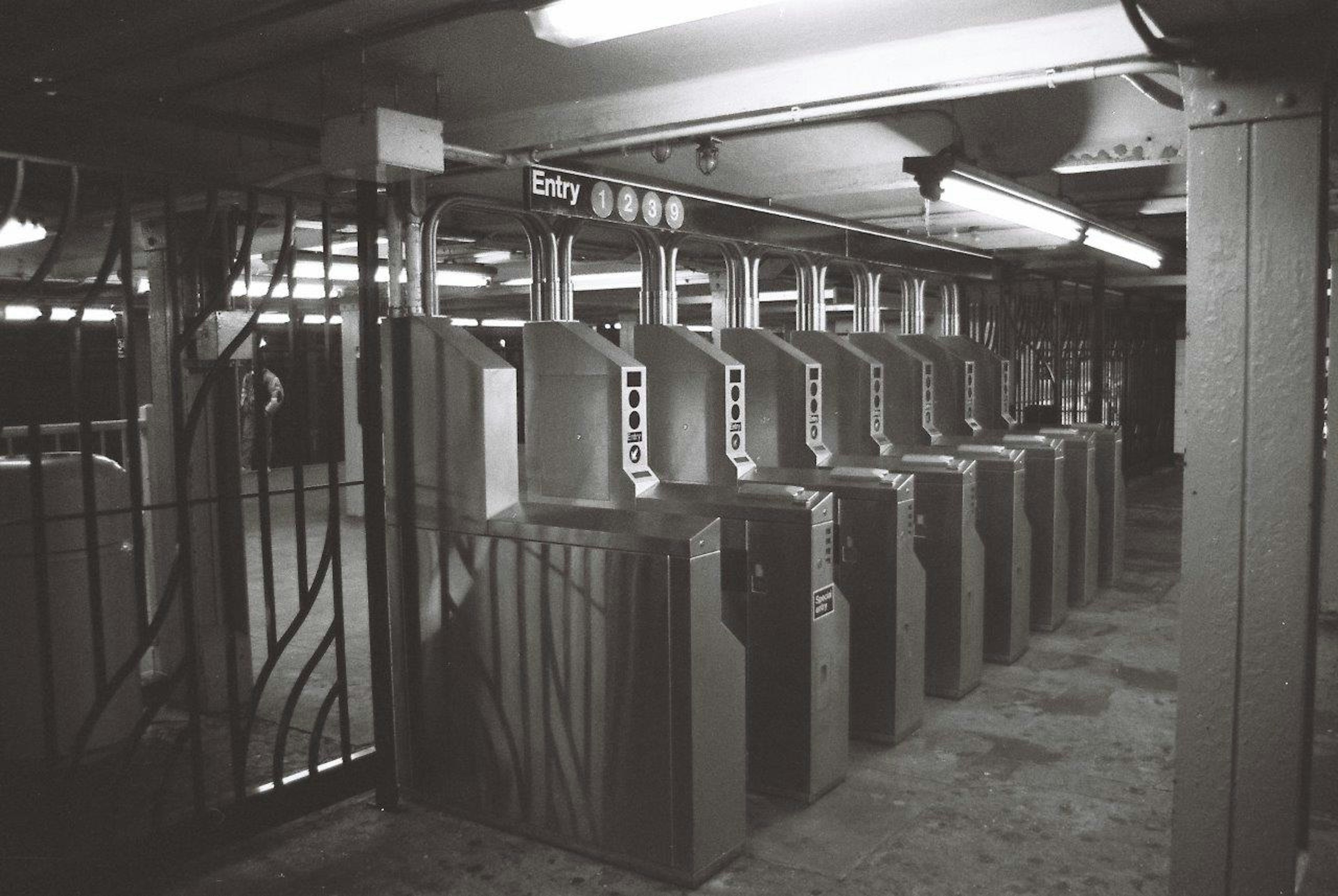 Black and white photo of subway turnstiles lined up