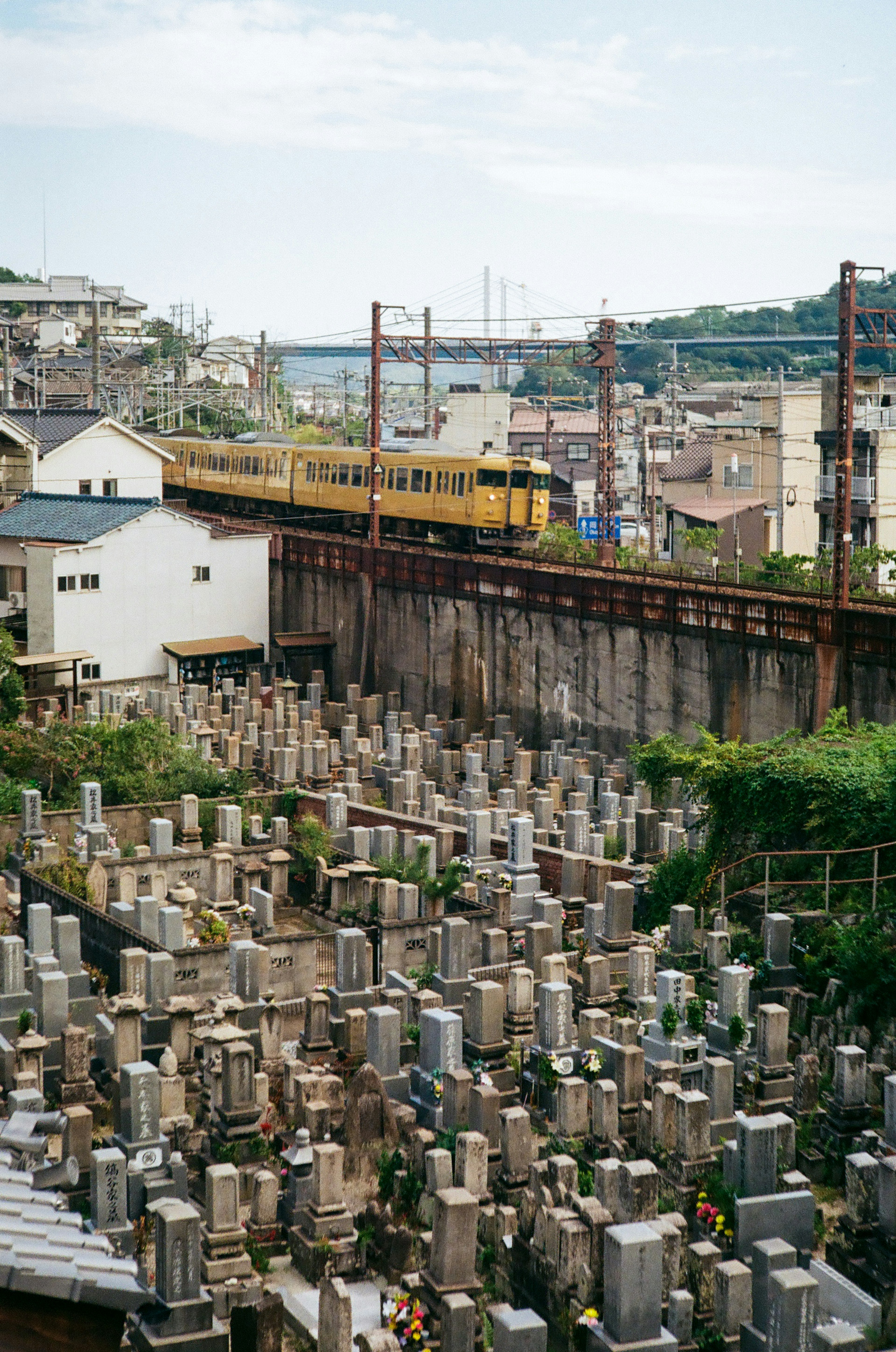 Una vista de un cementerio con lápidas y vías de tren al fondo