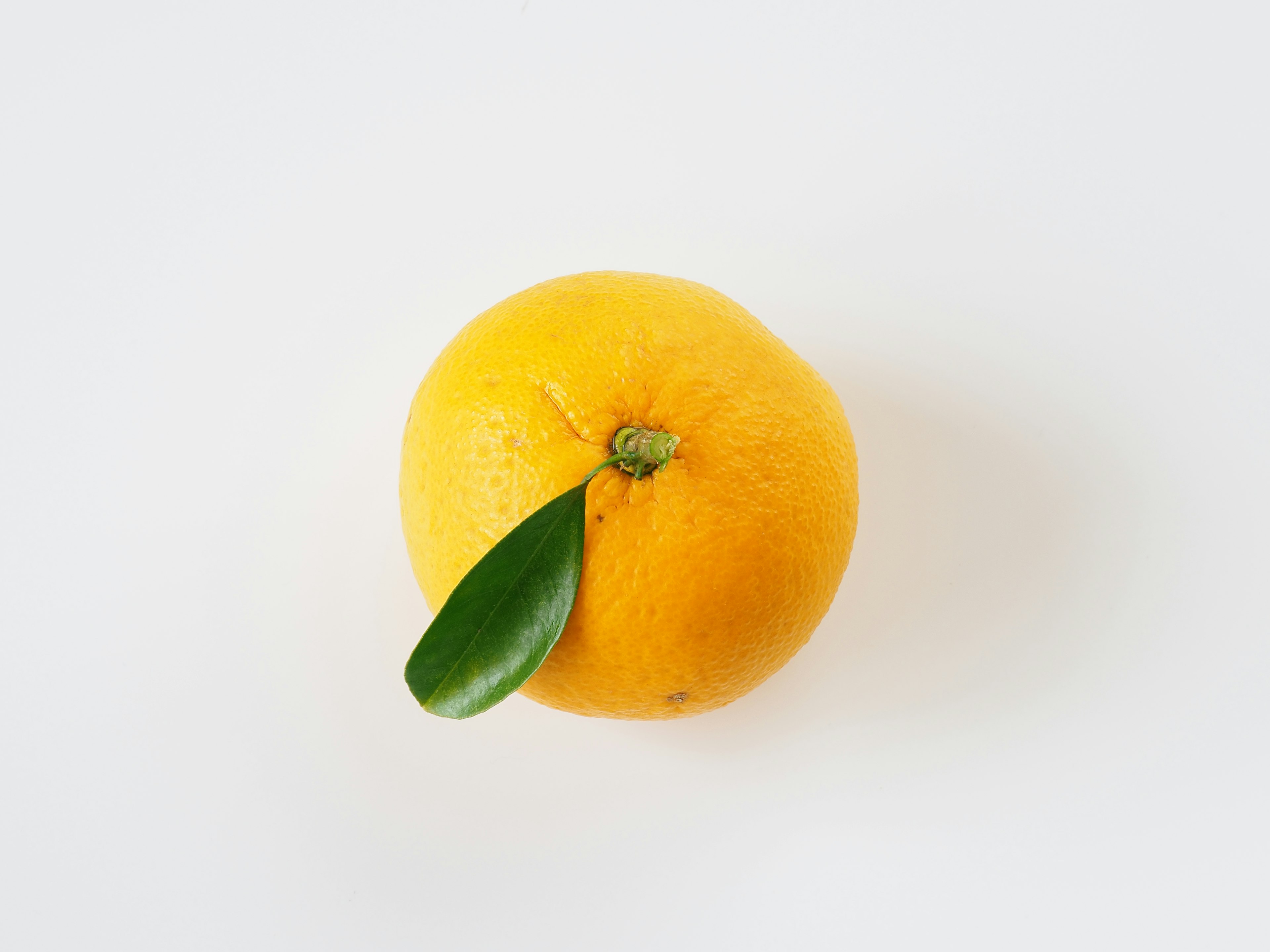 Bright yellow orange with green leaf attached