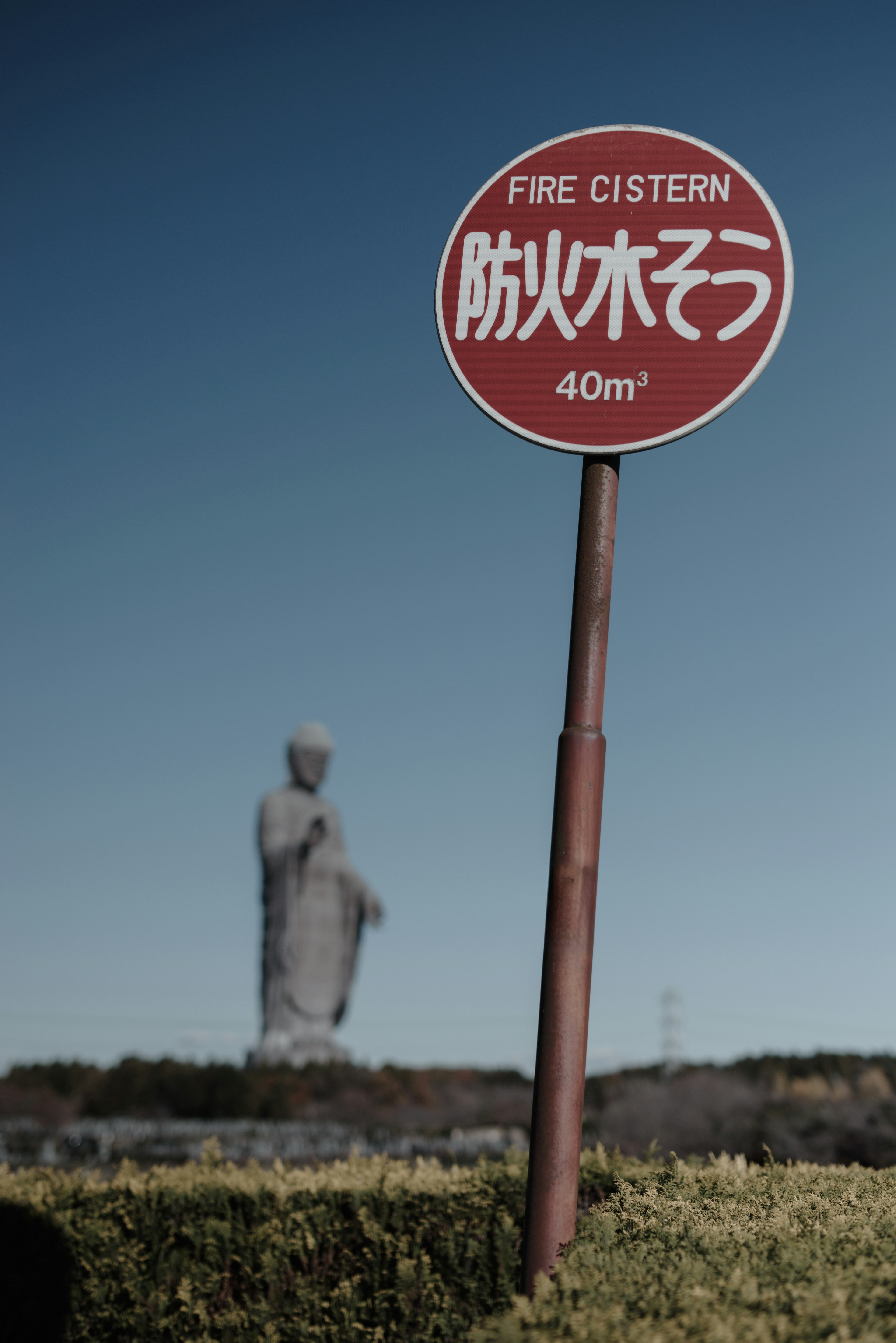 Cartello di cisterna antincendio con una grande statua di Buddha sullo sfondo