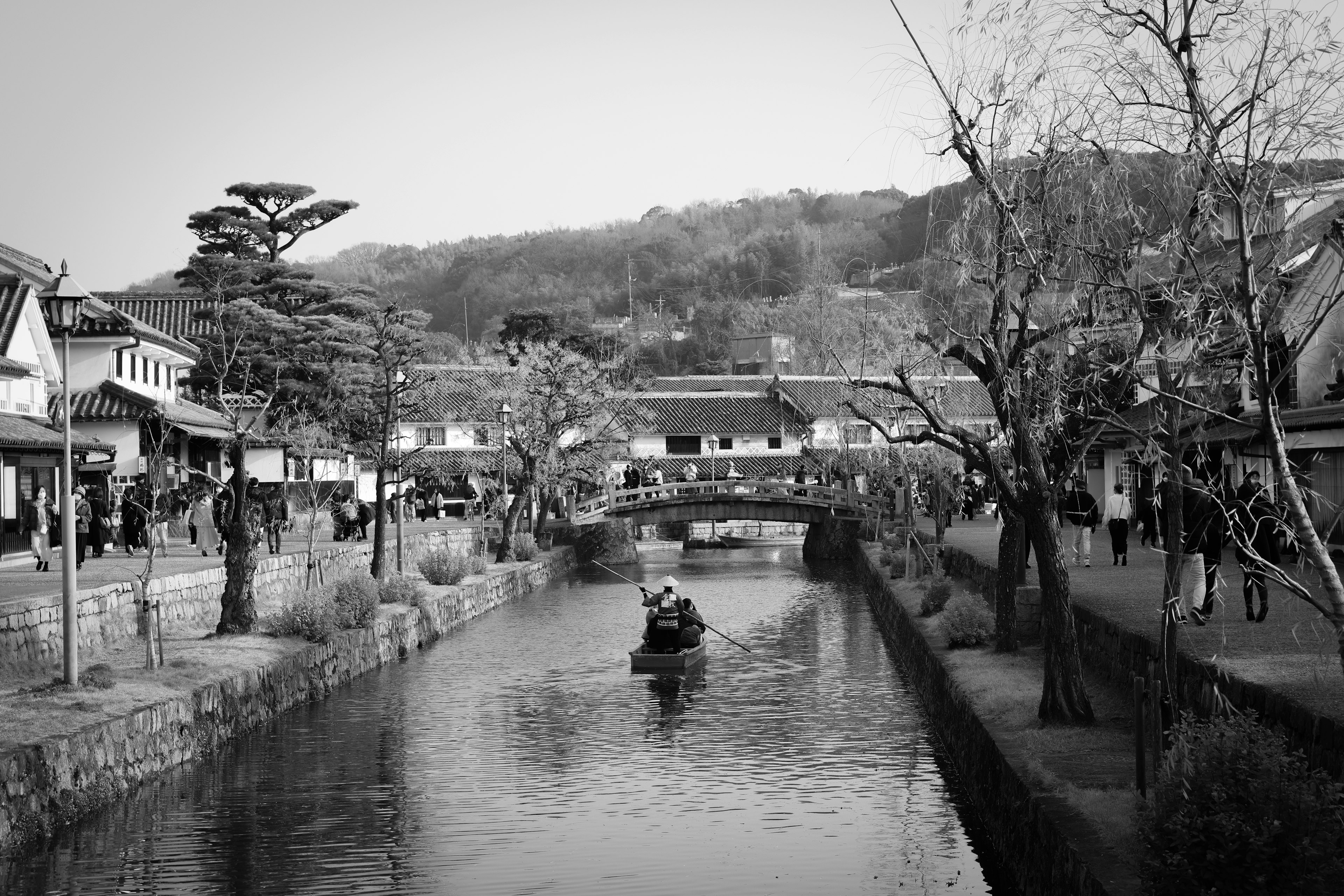 Escena en blanco y negro de un canal tranquilo con edificios históricos un bote deslizándose por el agua