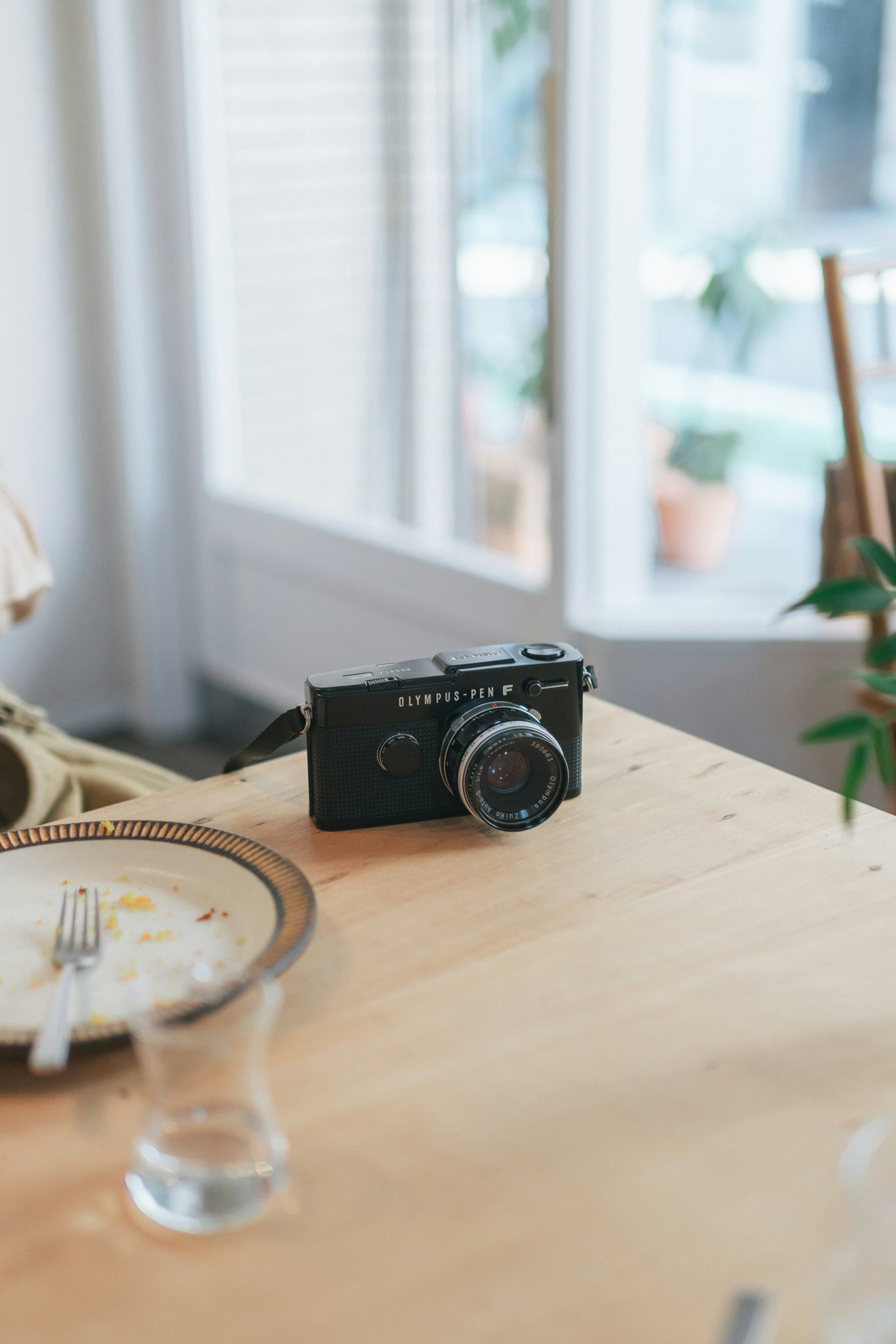 Appareil photo noir sur une table en bois avec une assiette et un verre