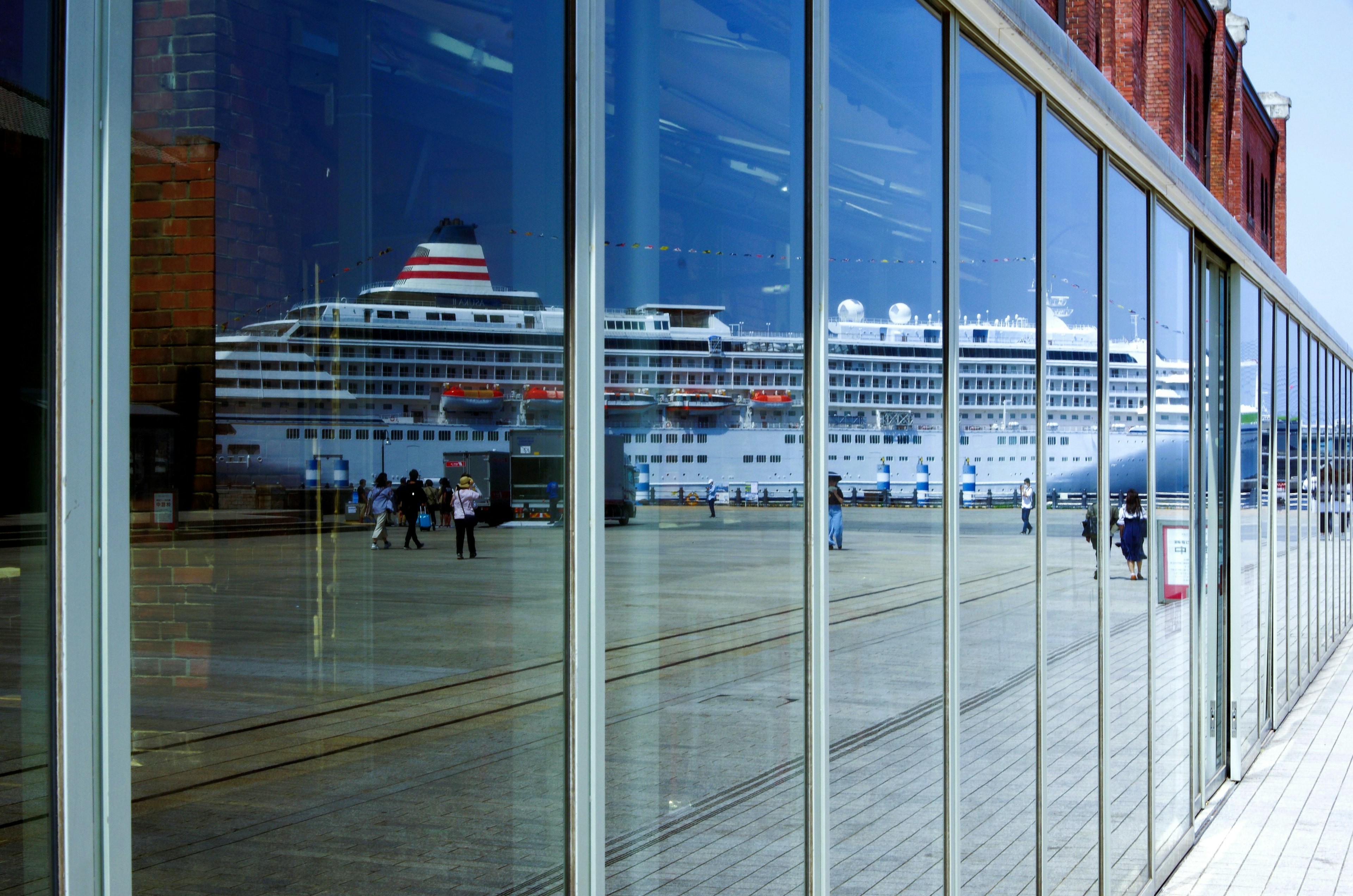 Reflets d'un navire de croisière et de personnes dans des fenêtres en verre