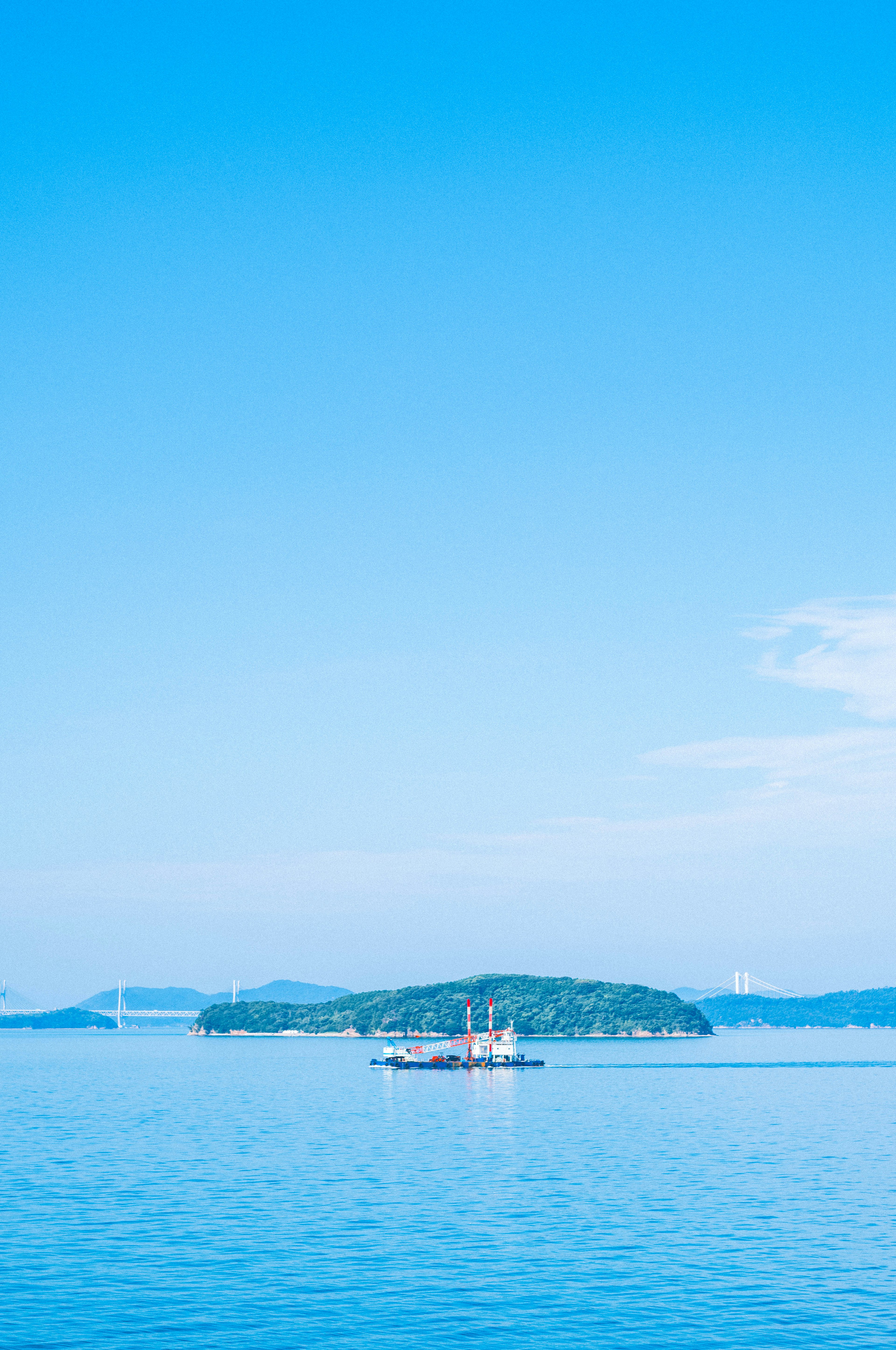 青い空と穏やかな海に浮かぶ小さな島と船