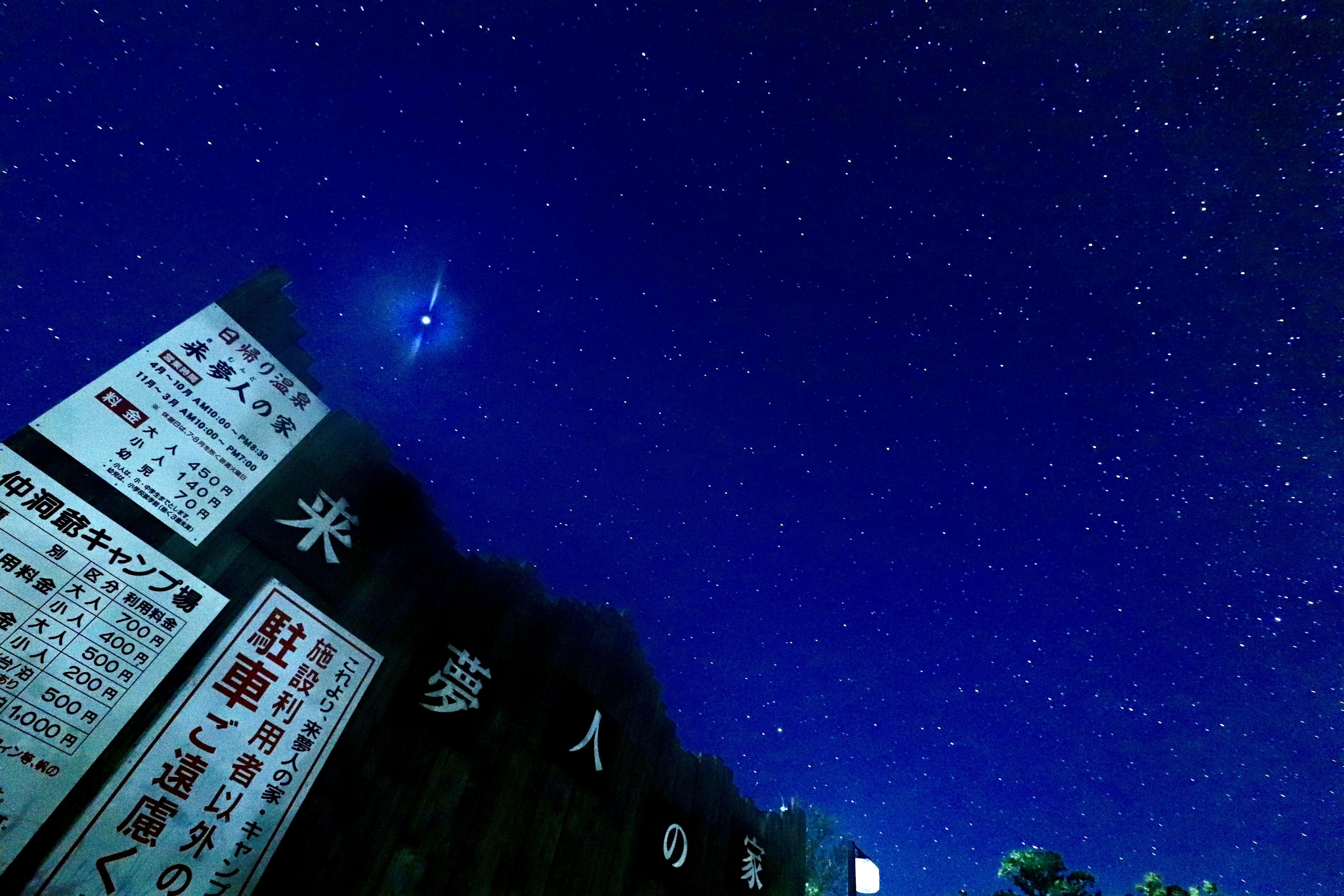 A cluster of signs under a starry sky with a deep blue background