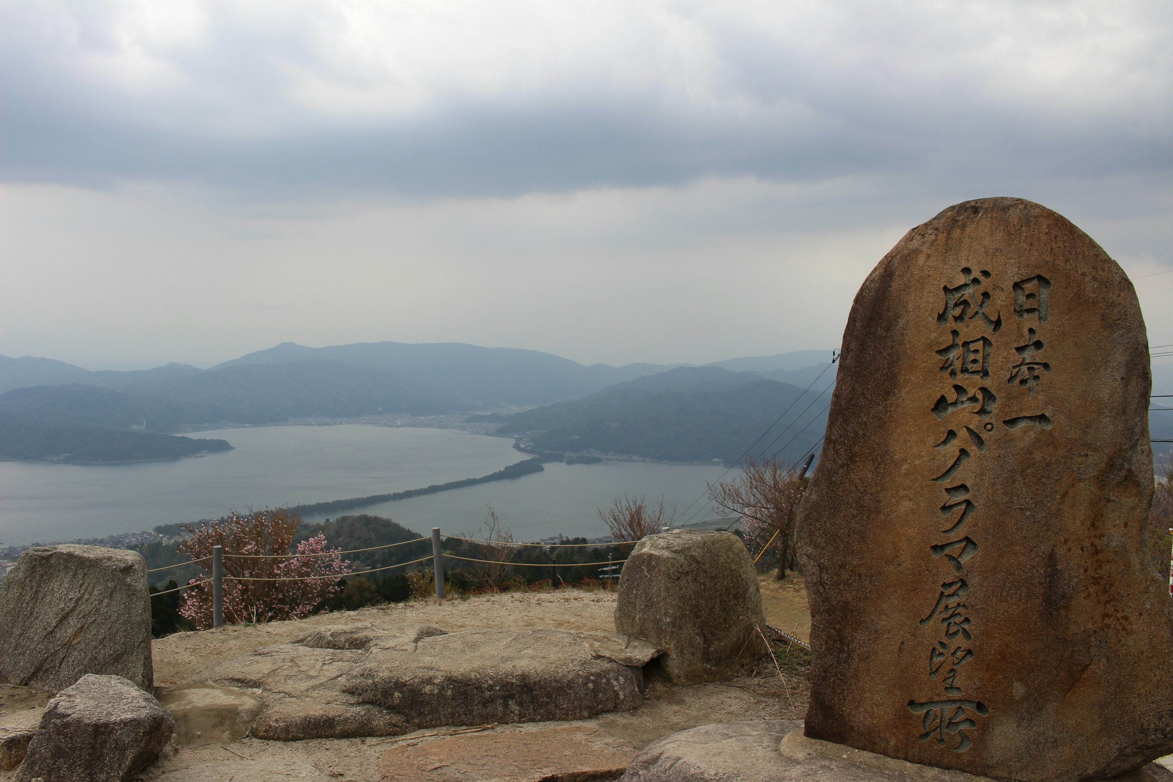 Scenic view of a lake from a mountain peak with an ancient stone monument