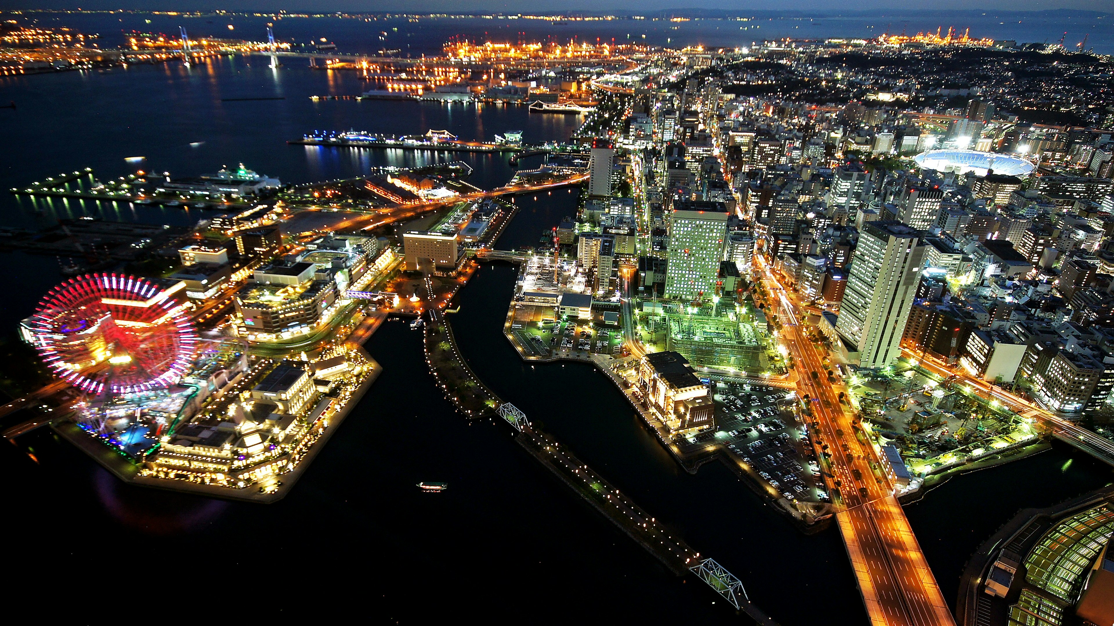 夜景の都市風景、海と建物の明かり、観覧車の色鮮やかさ