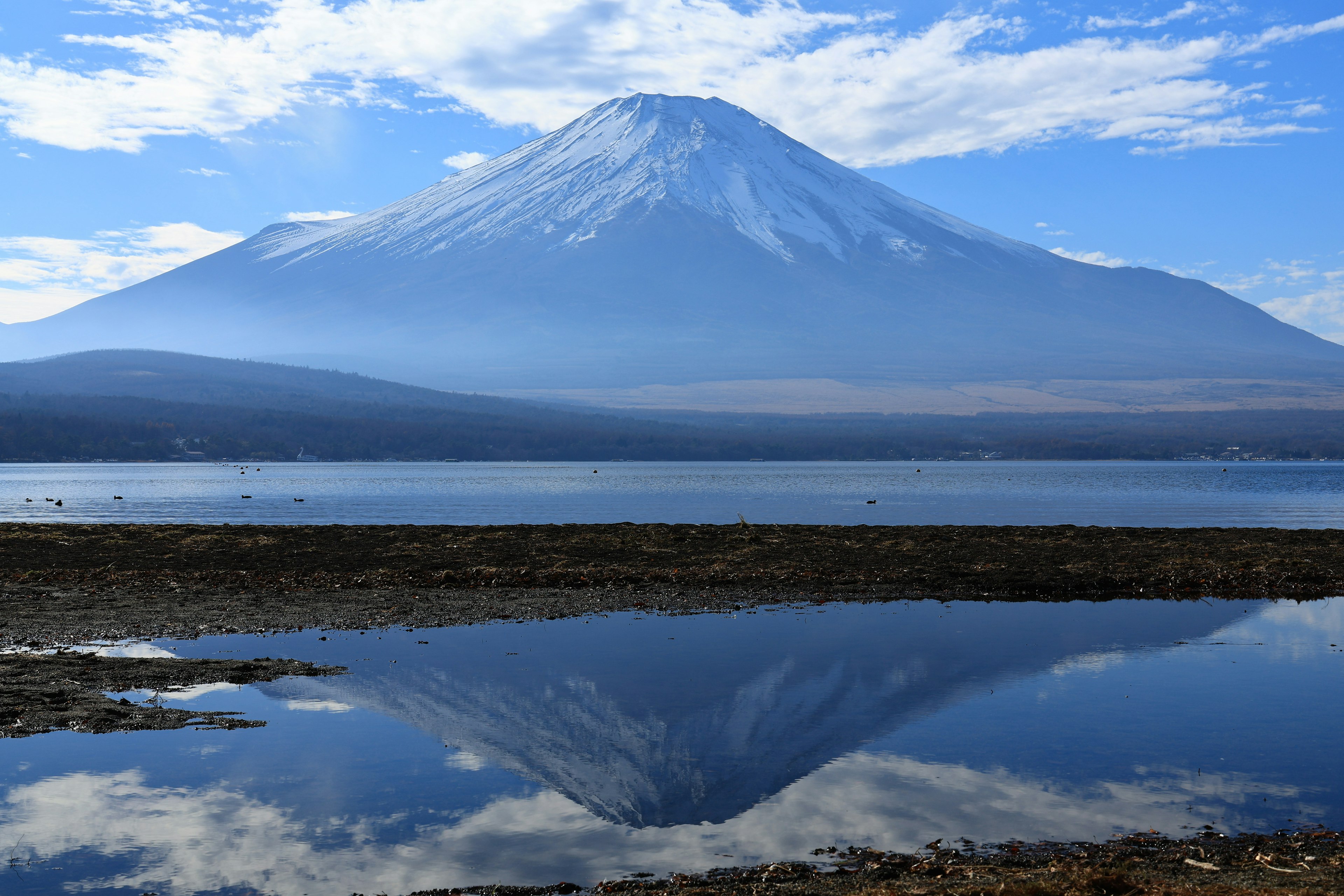 ทิวทัศน์ที่สวยงามของภูเขาฟูจิพร้อมการสะท้อนในทะเลสาบและท้องฟ้าสีฟ้า