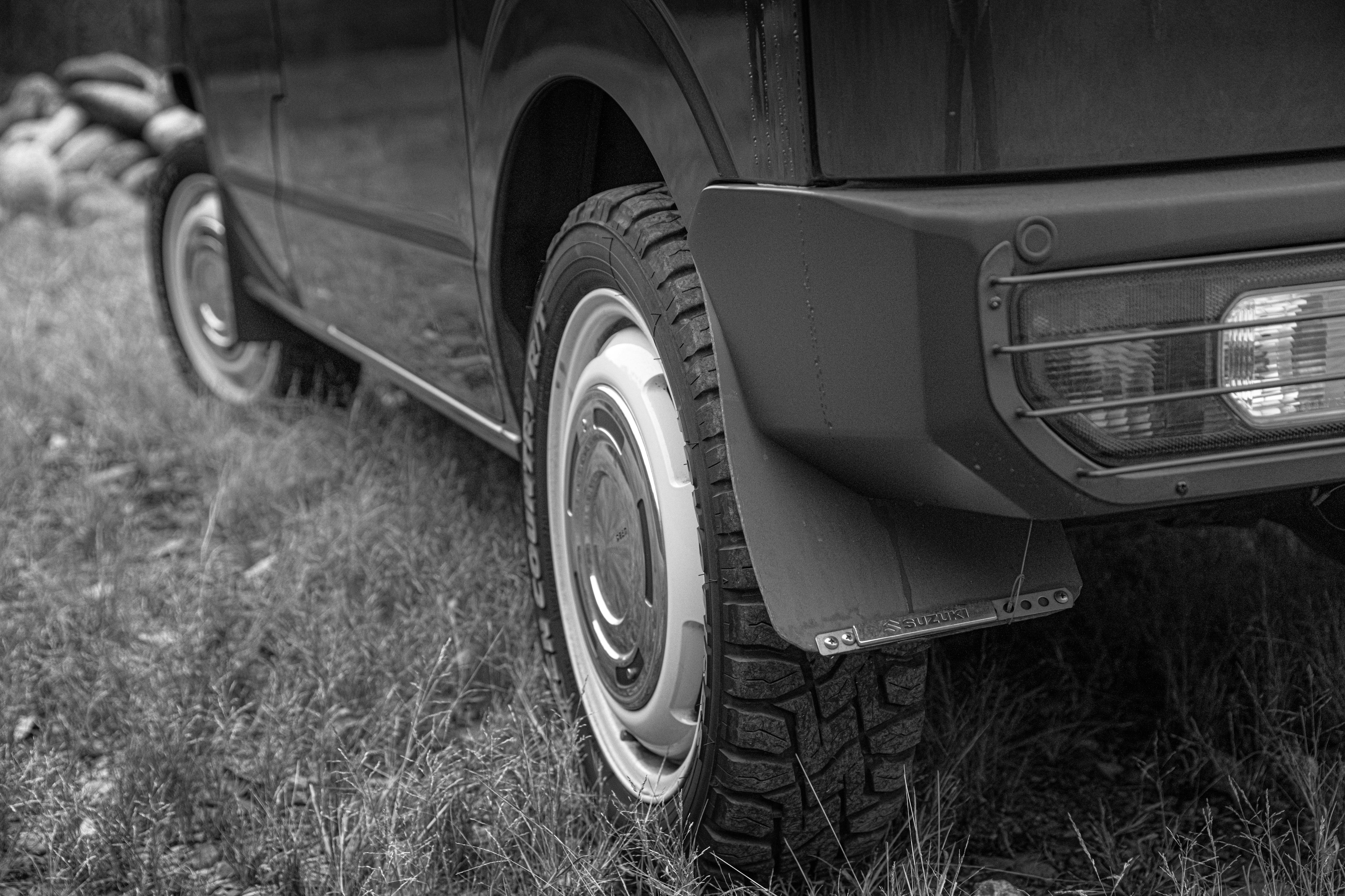 Black and white photo of a car's rear tire and bumper