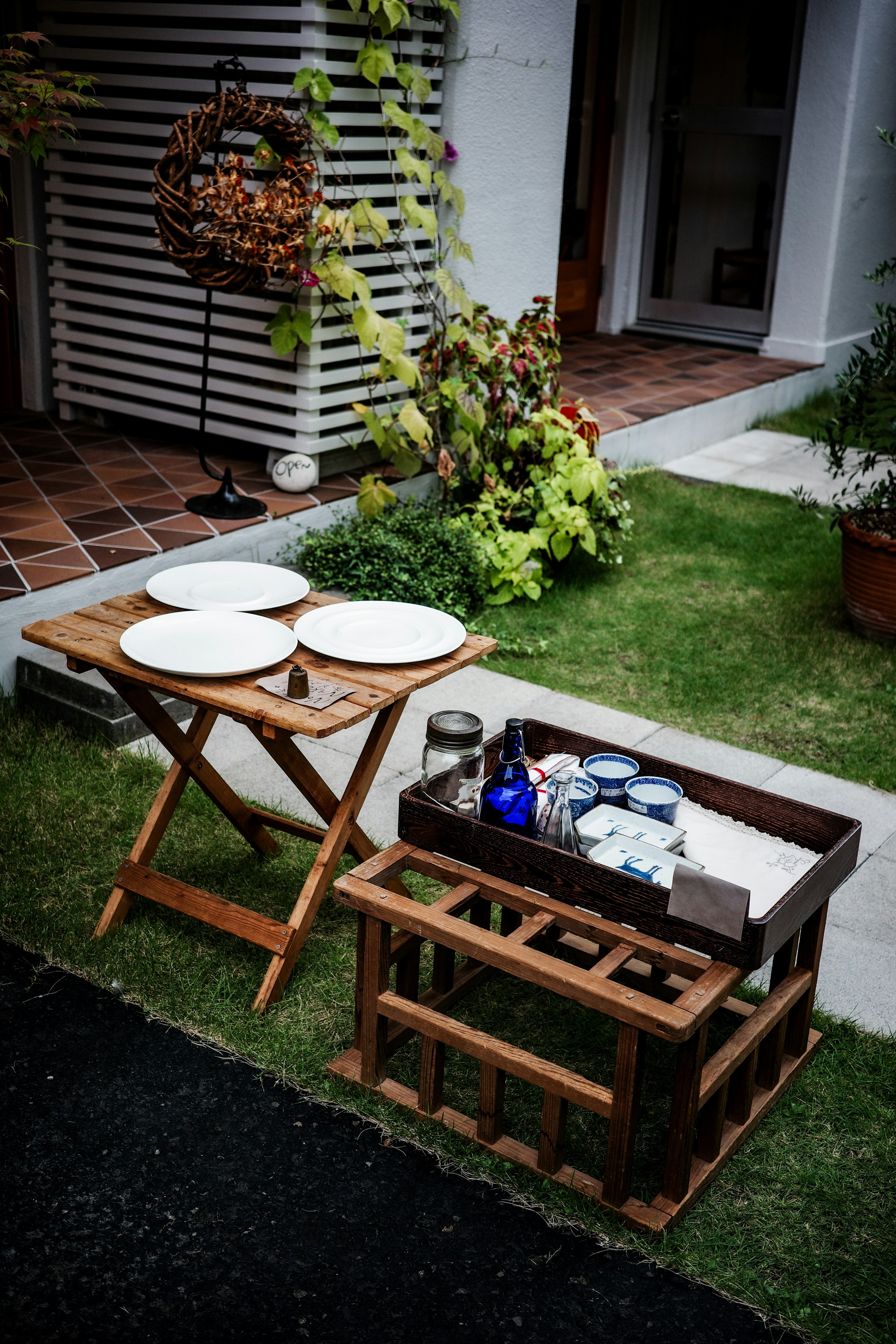 Table en bois dans un jardin avec des assiettes et des ustensiles de cuisine