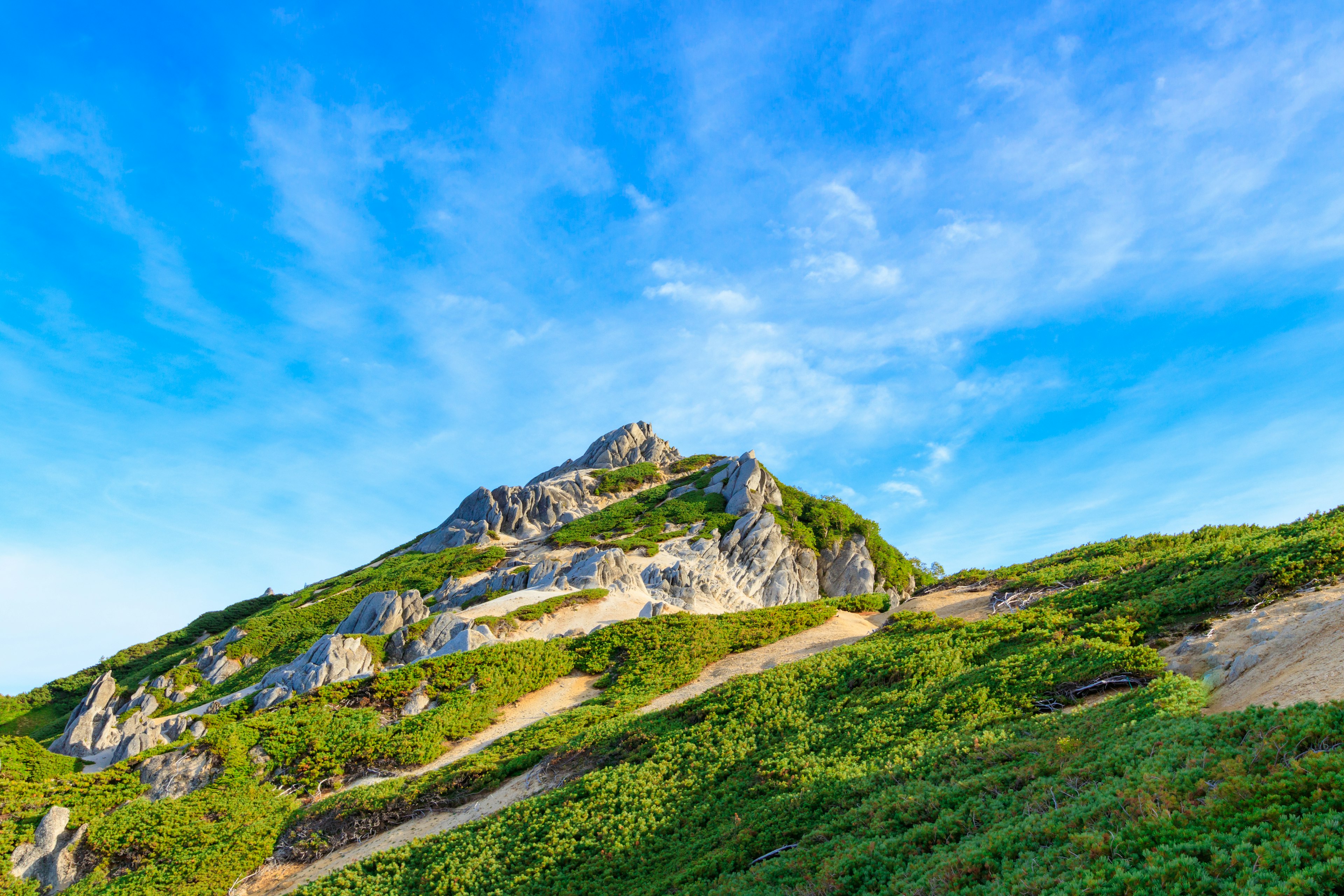 Berglandschaft umgeben von blauem Himmel und grünem Gras