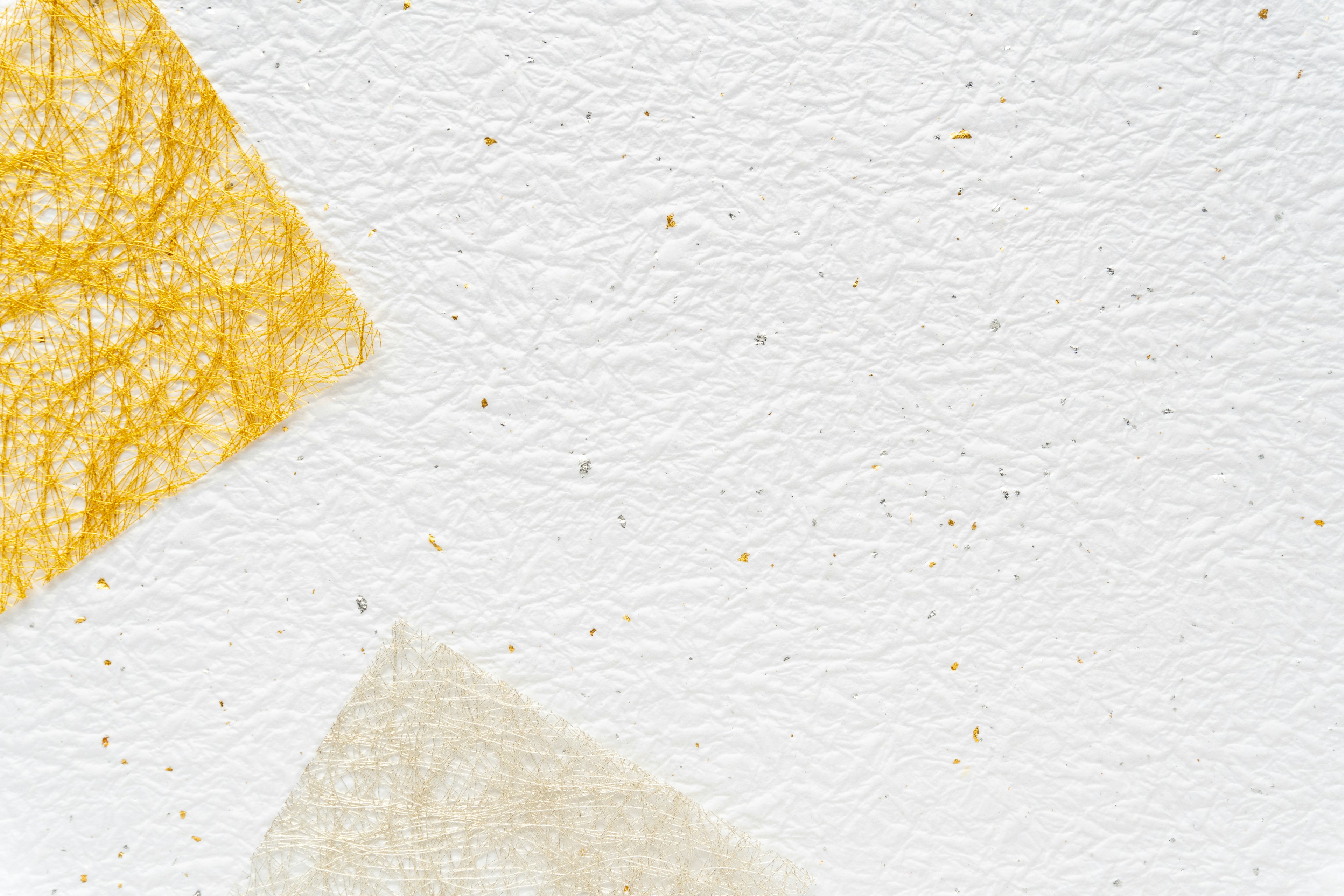 Irregular shapes of yellow and cream paper on a white background