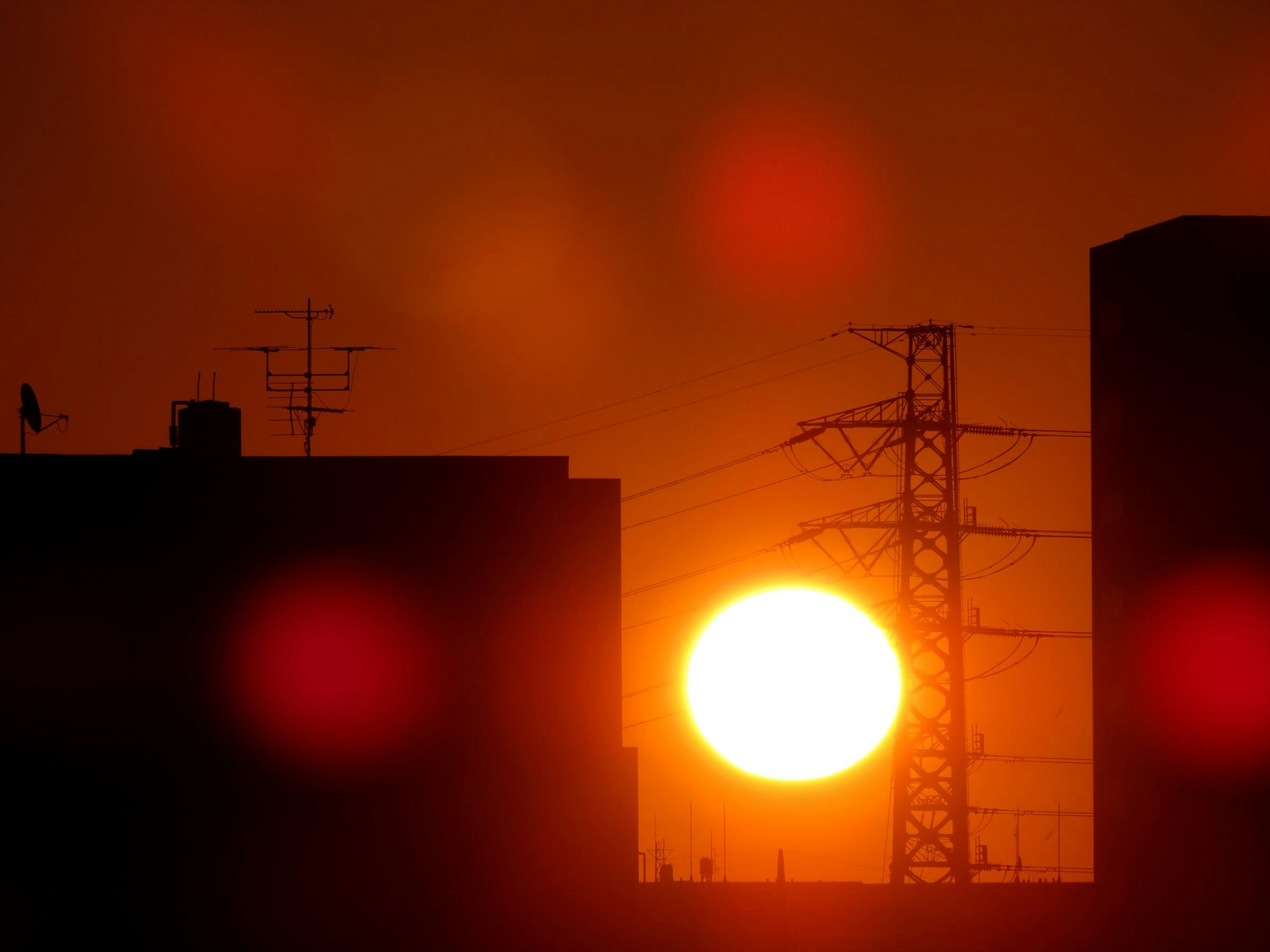 Coucher de soleil derrière des bâtiments avec silhouettes et lignes électriques