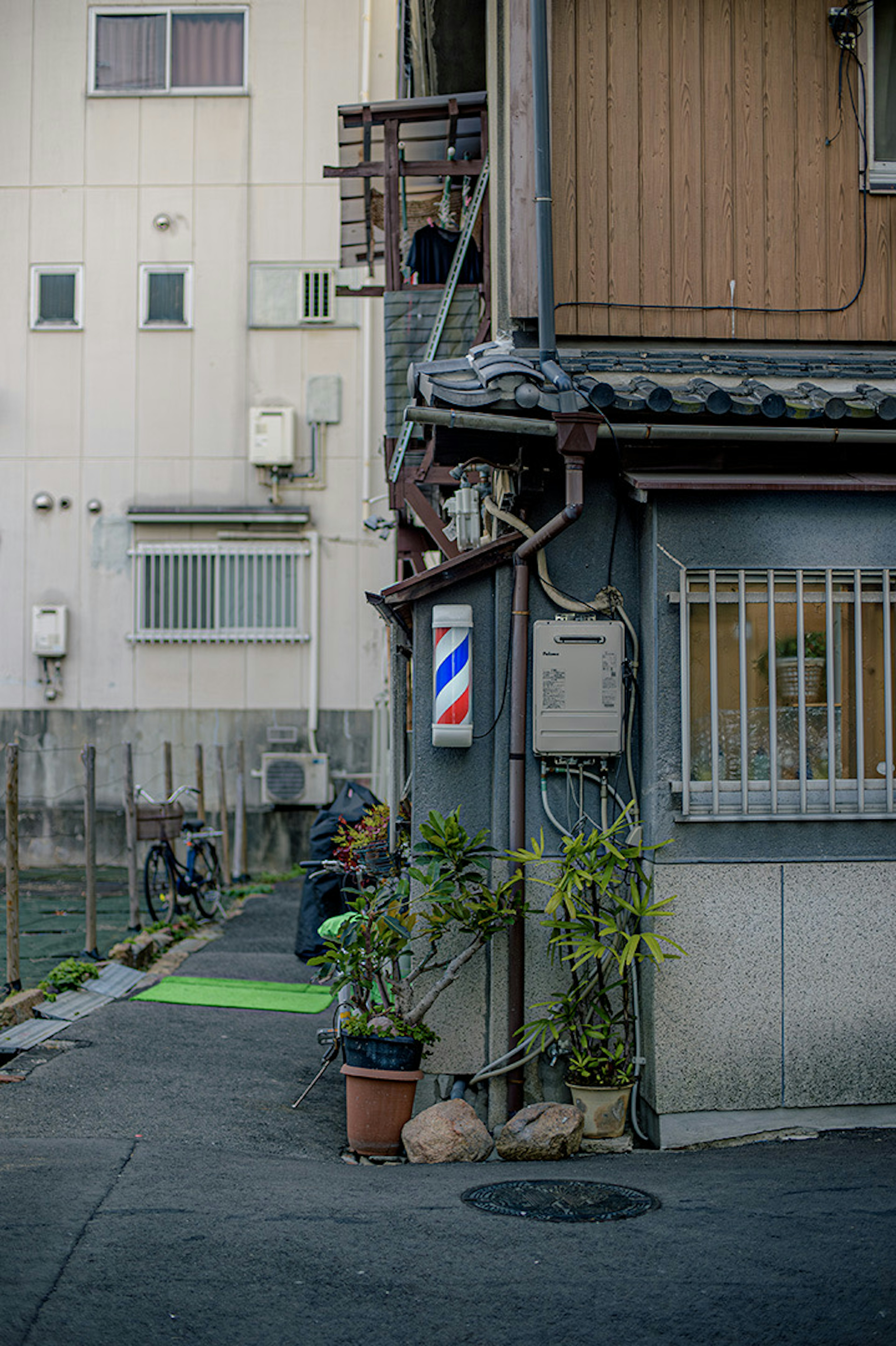 Extérieur d'un salon de coiffure dans une ruelle étroite avec un chemin vert et des plantes