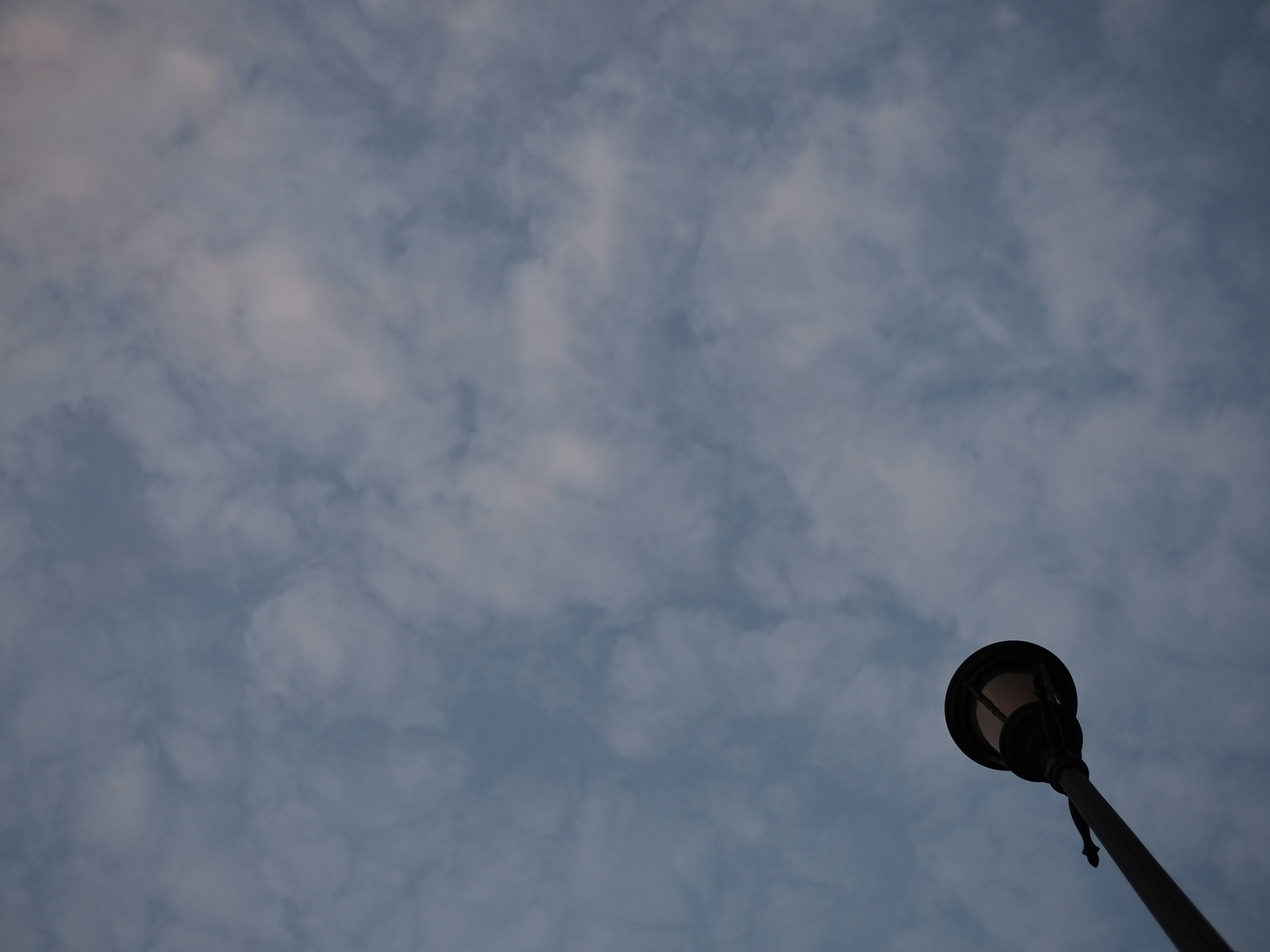 青空と薄い雲が広がる背景の下にある街灯