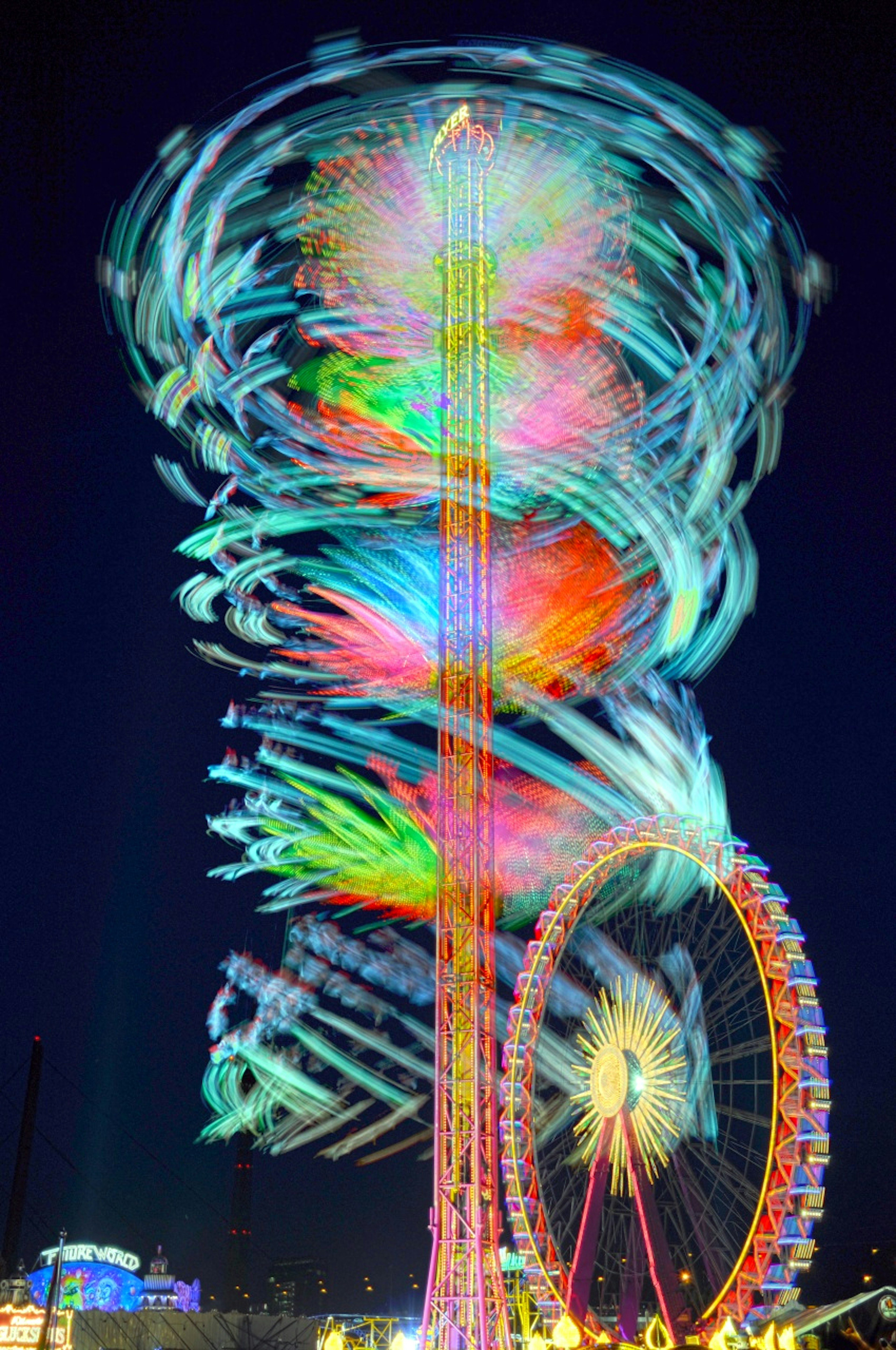 Luci colorate che vorticano di una ruota panoramica e di una torre nel cielo notturno