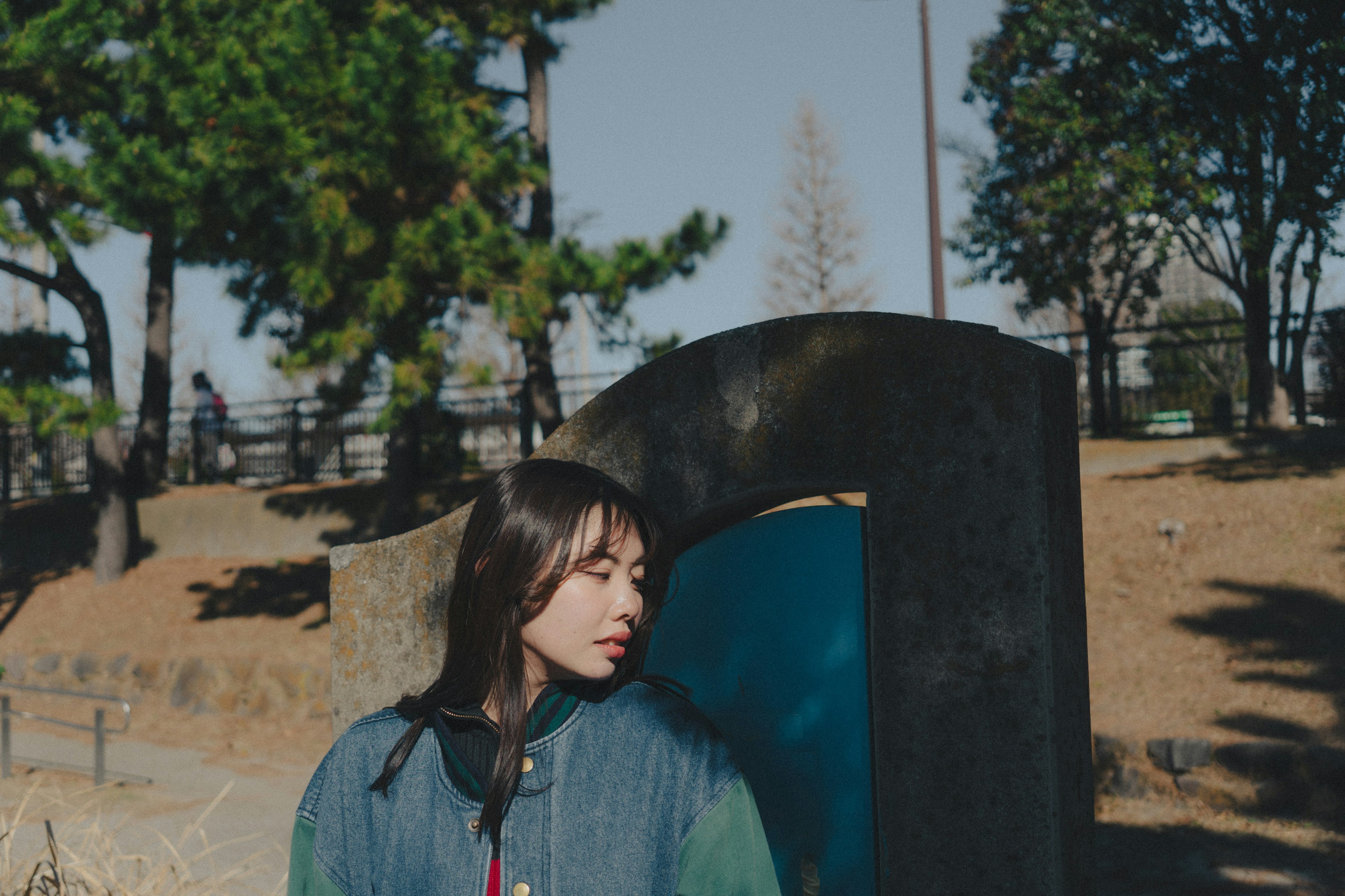 公園で青い背景に寄りかかる女性のポートレート