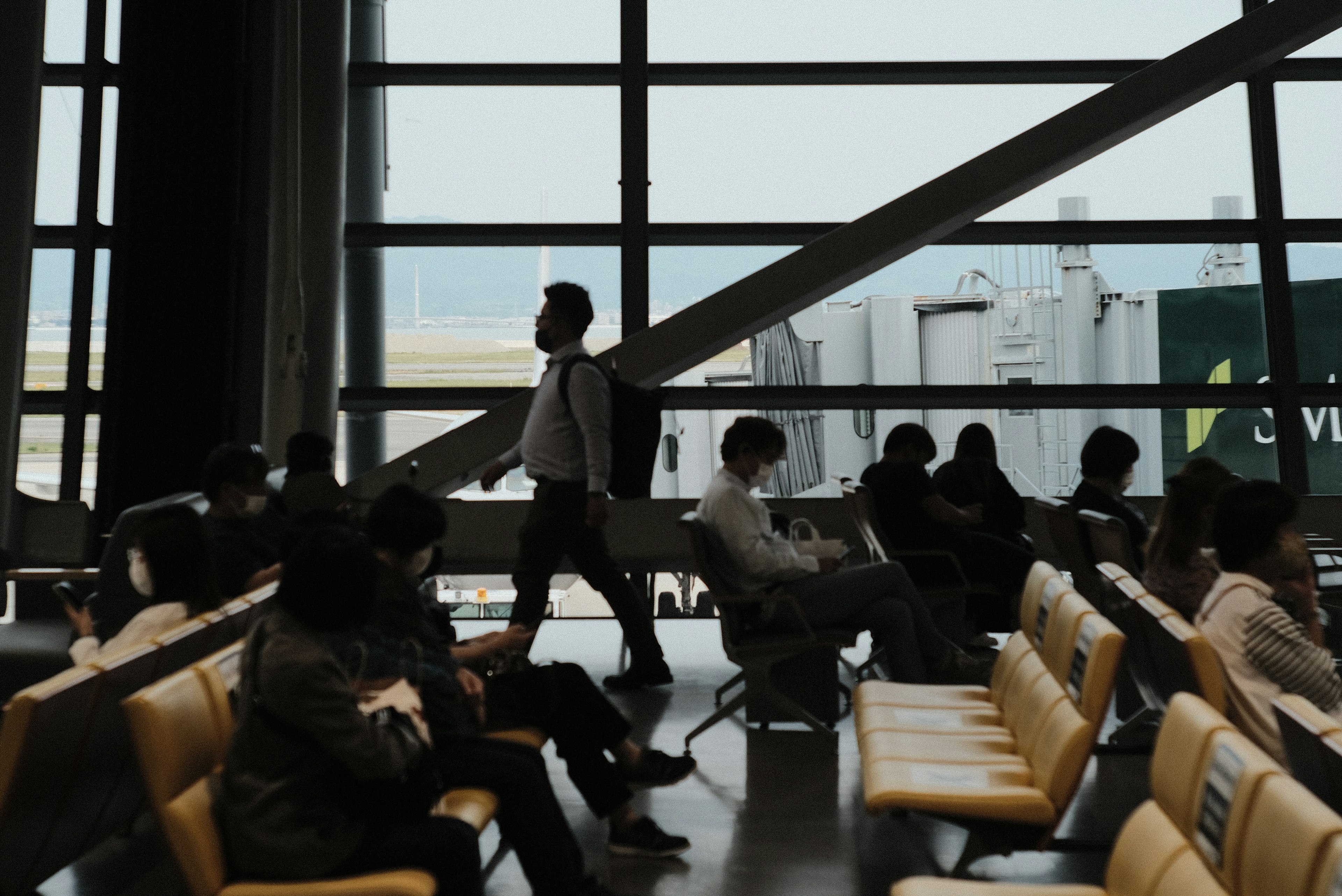 空港の待合室で歩く男性と座っている人々