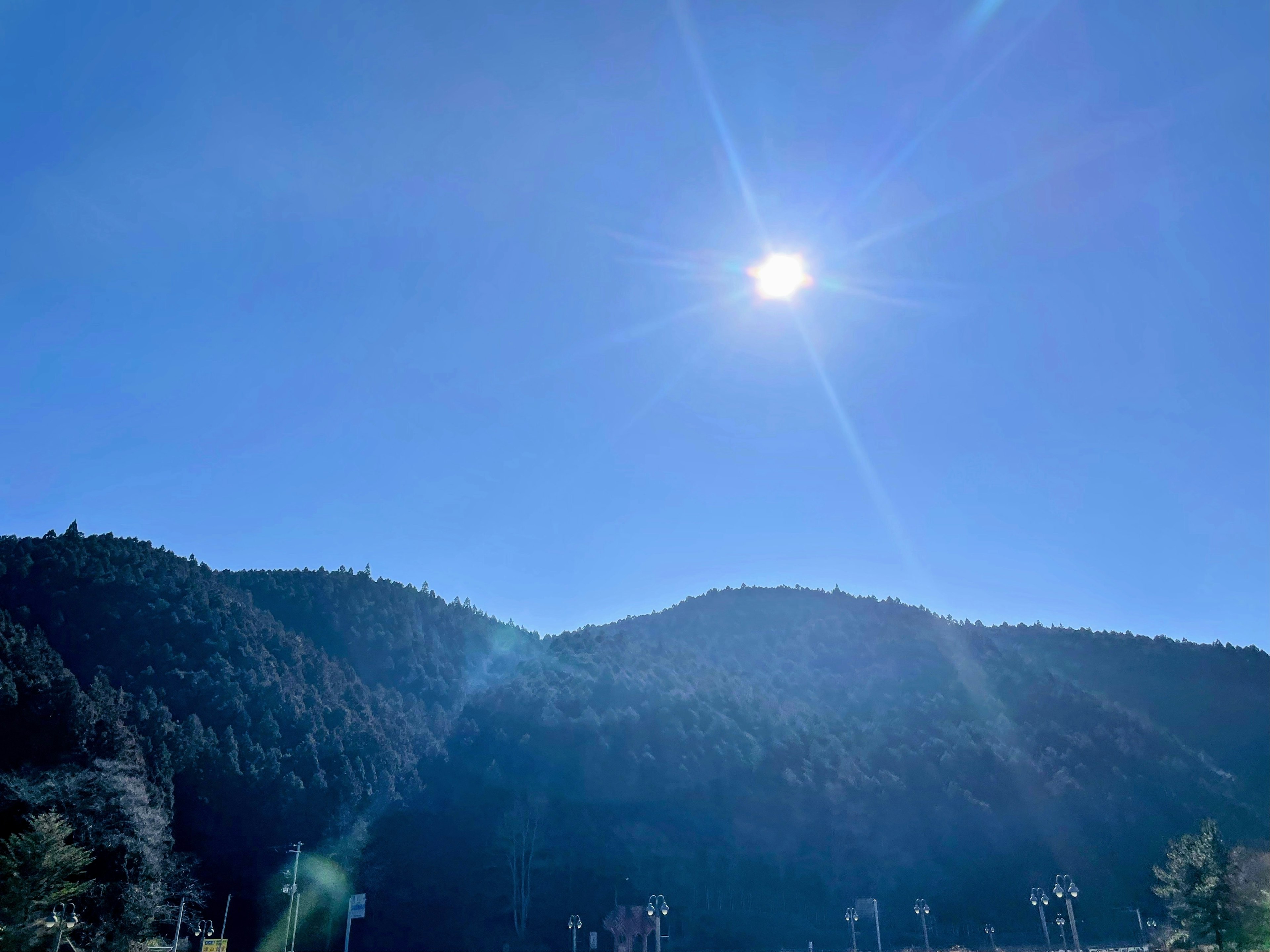 Heller Sonnenschein über grünen Bergen unter einem klaren blauen Himmel