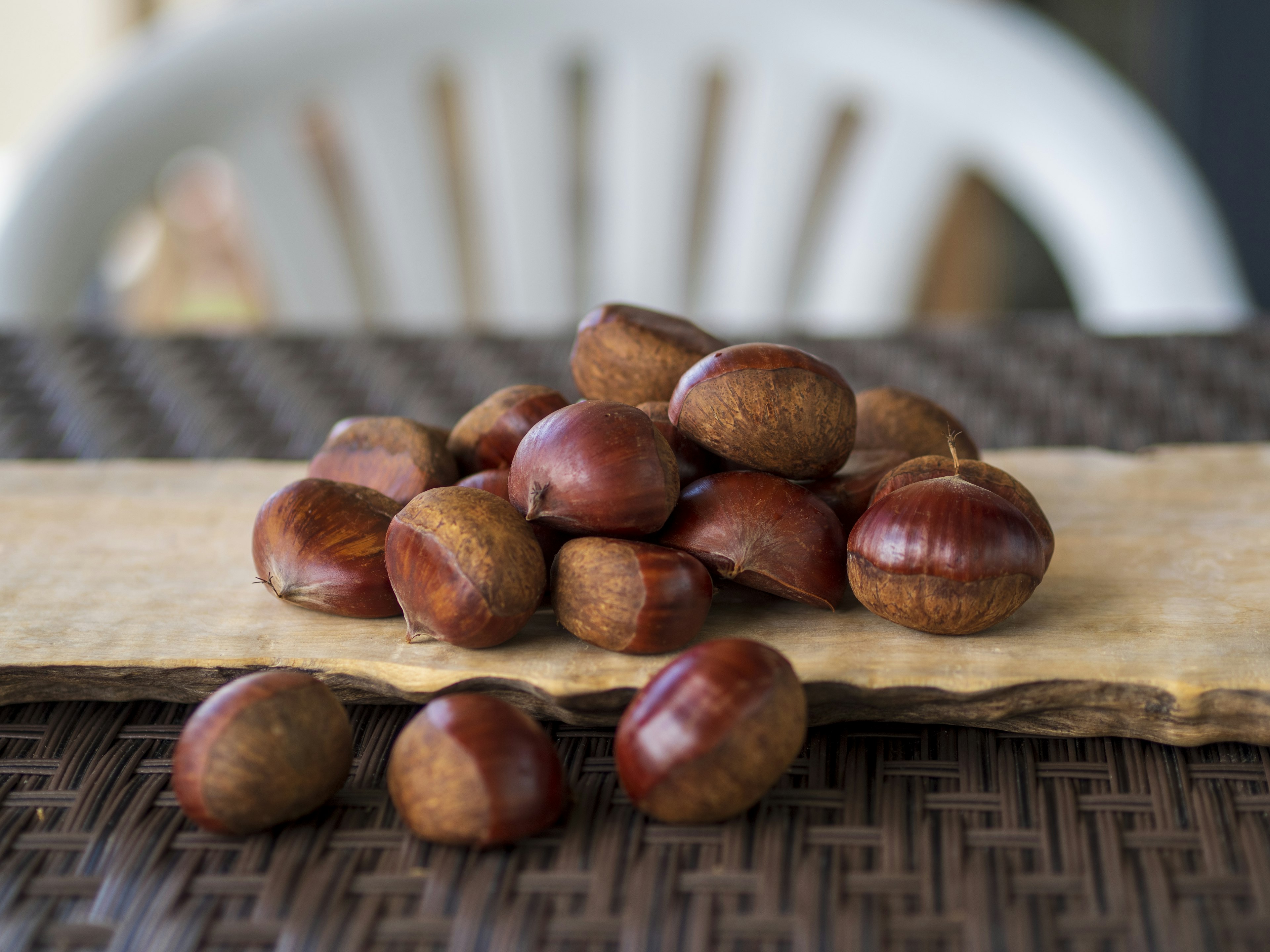 A pile of chestnuts on a wooden surface with a textured background