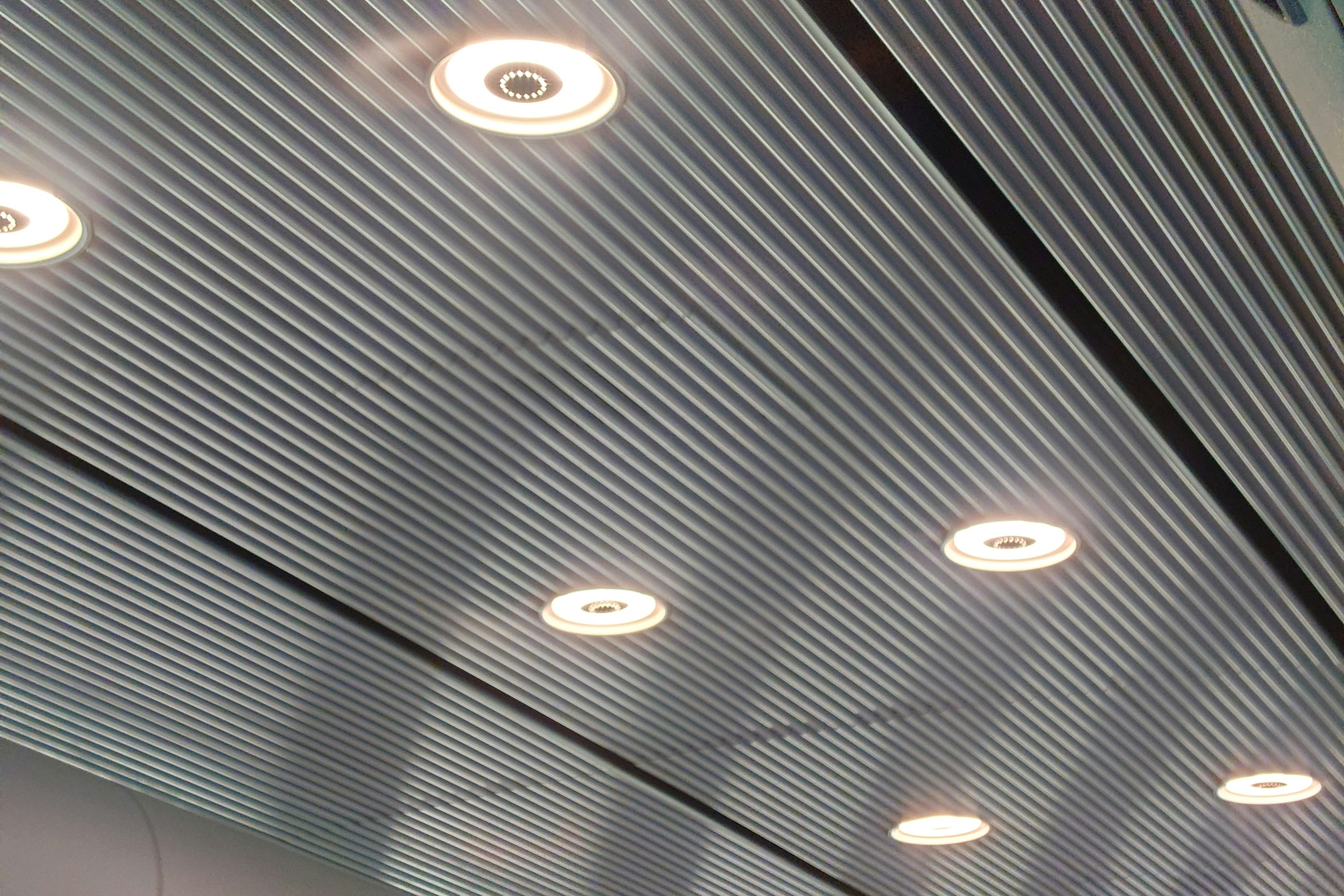 Metallic wavy ceiling with embedded round light fixtures