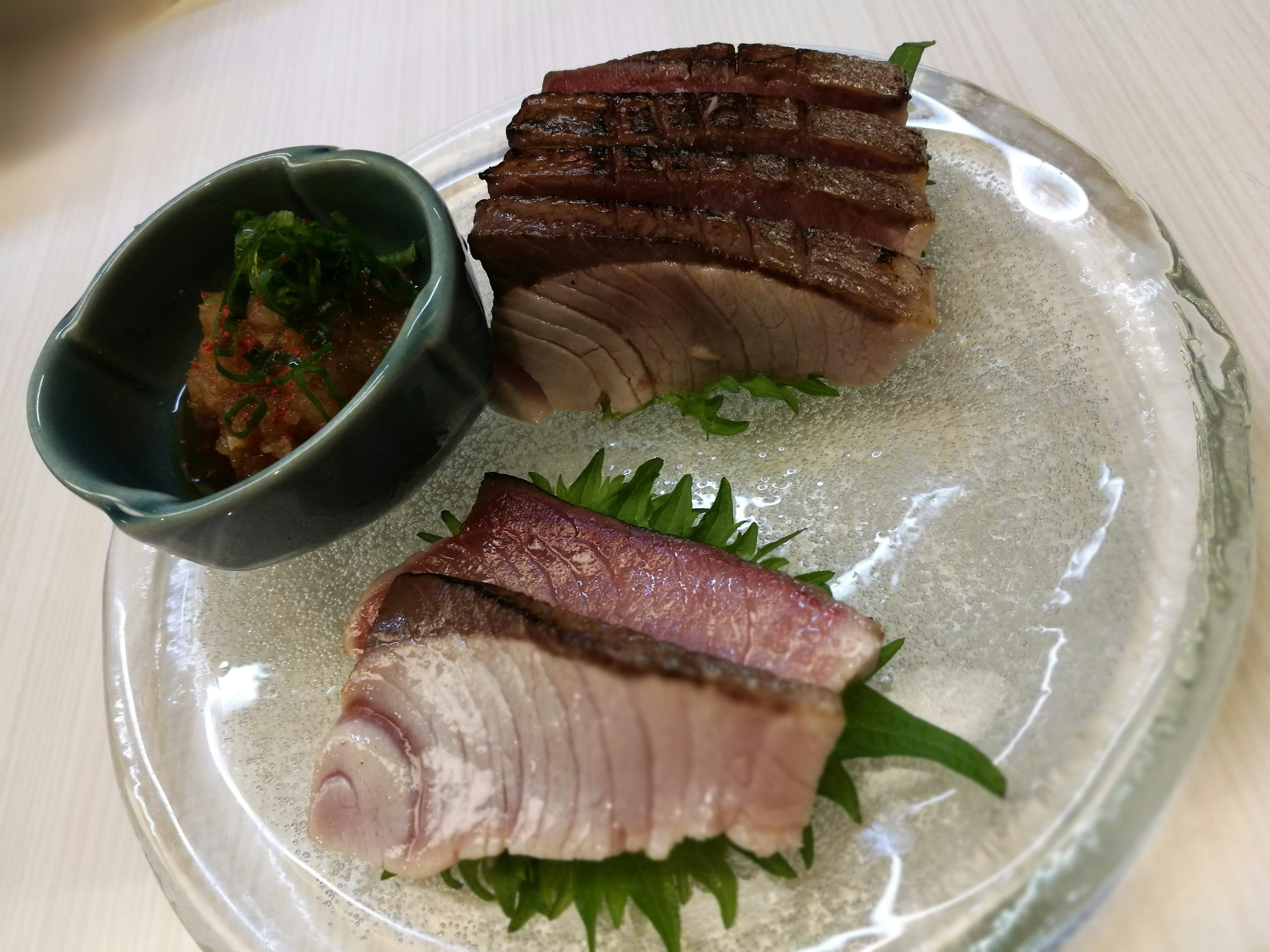 Sashimi fresco en un plato con un pequeño tazón de salsa