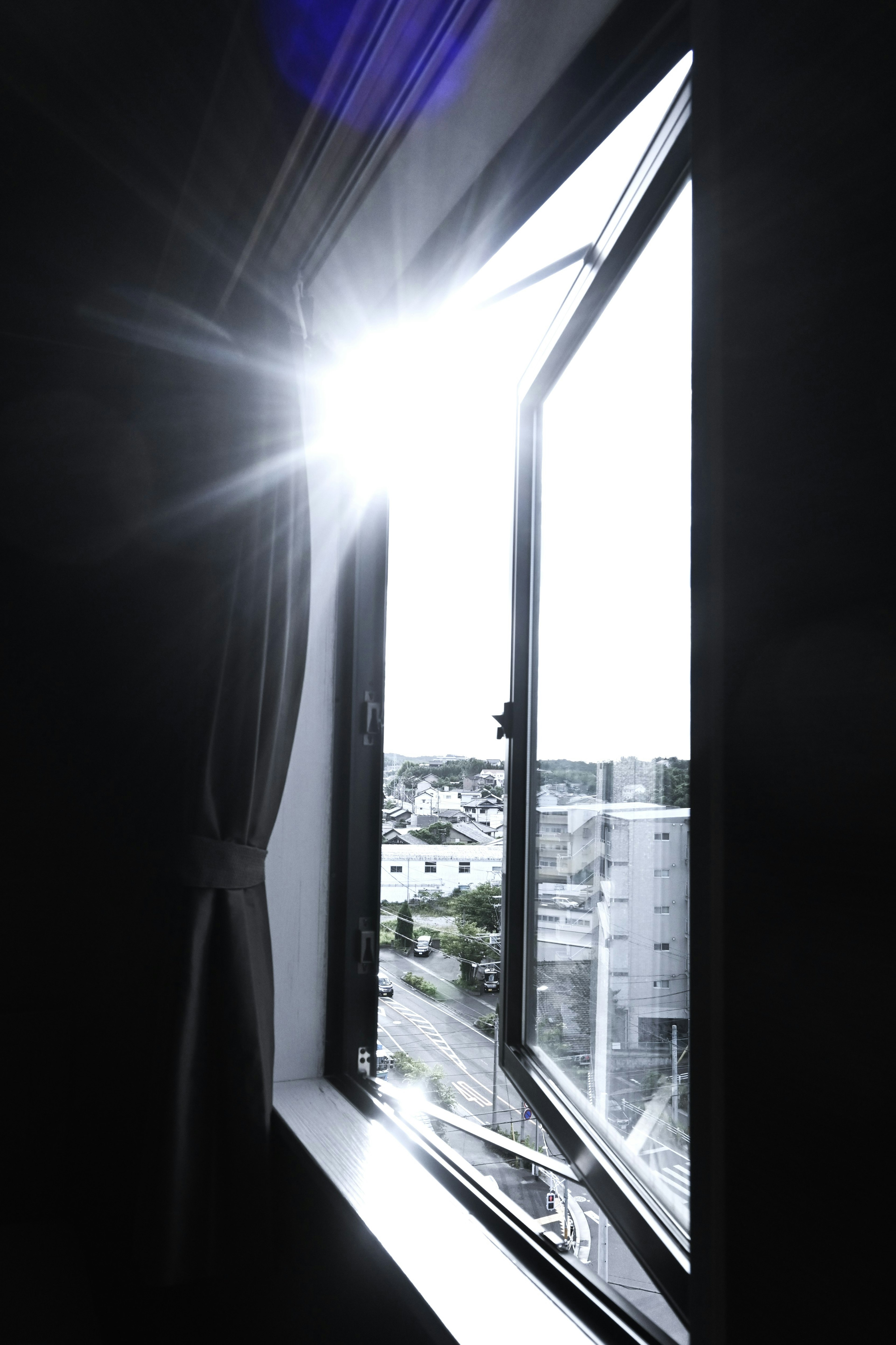 A corner of a room with sunlight streaming through an open window showcasing the outside view