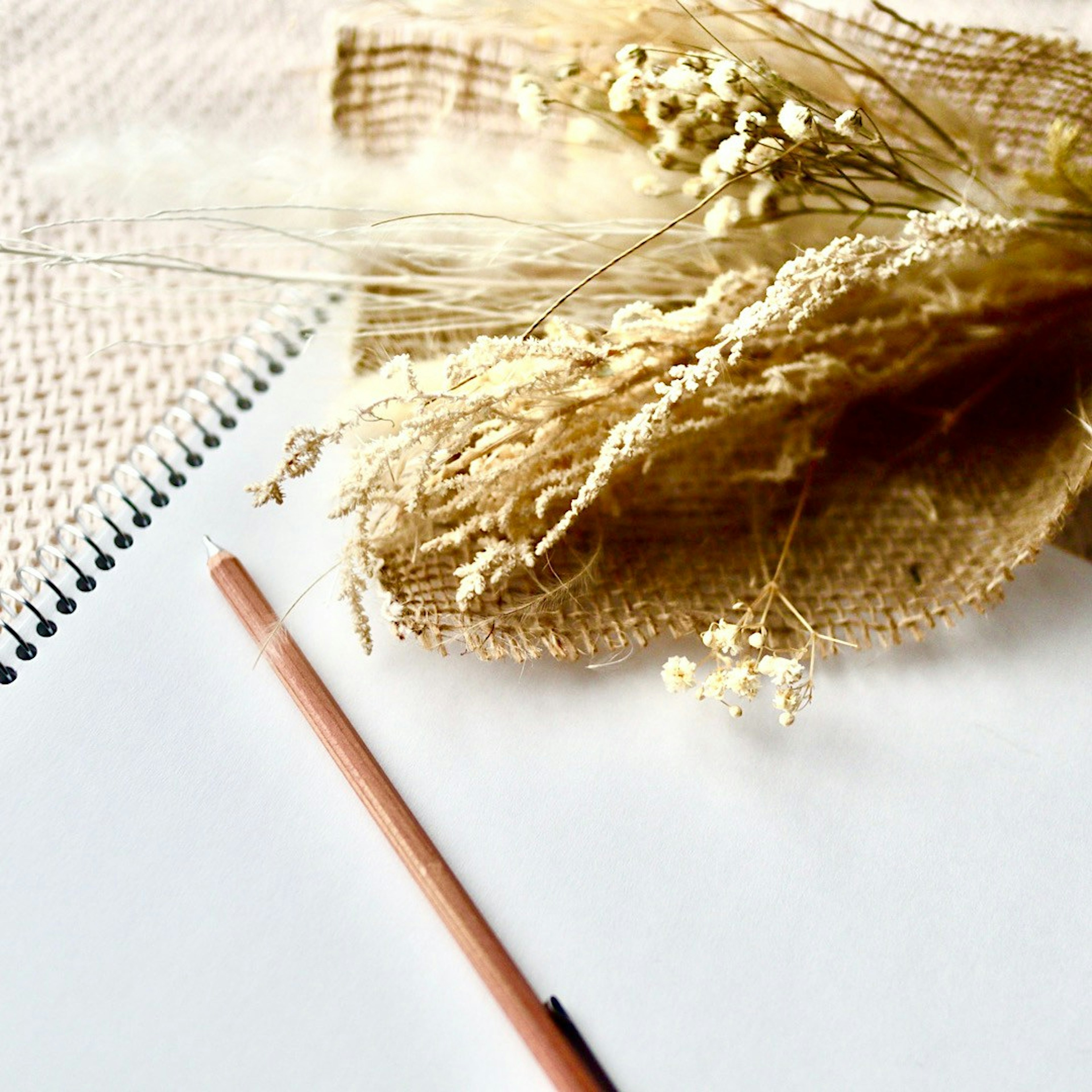 A dried bouquet placed next to a blank notebook and a pencil