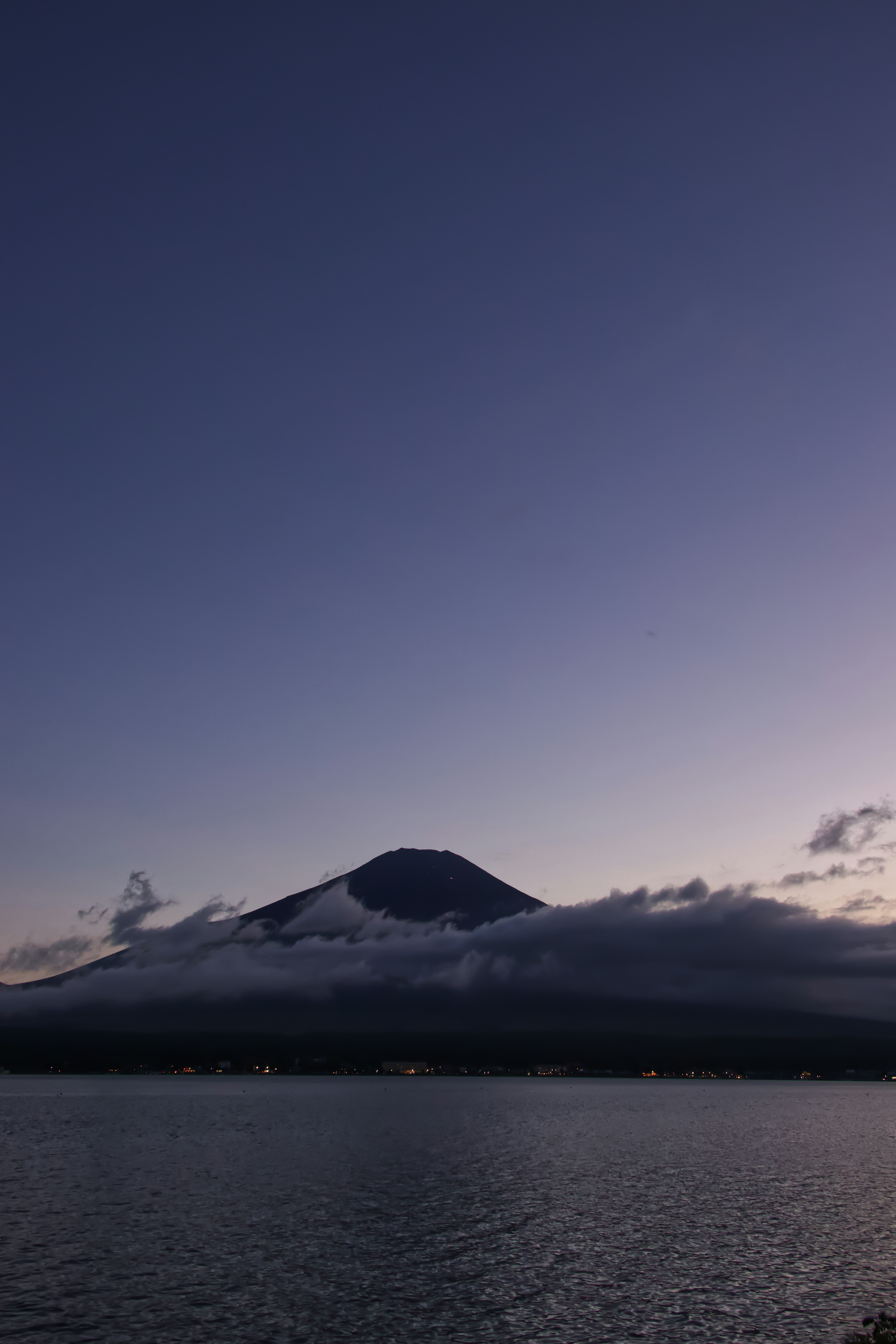 Gunung Fuji yang tertutup awan saat pemandangan senja yang tenang