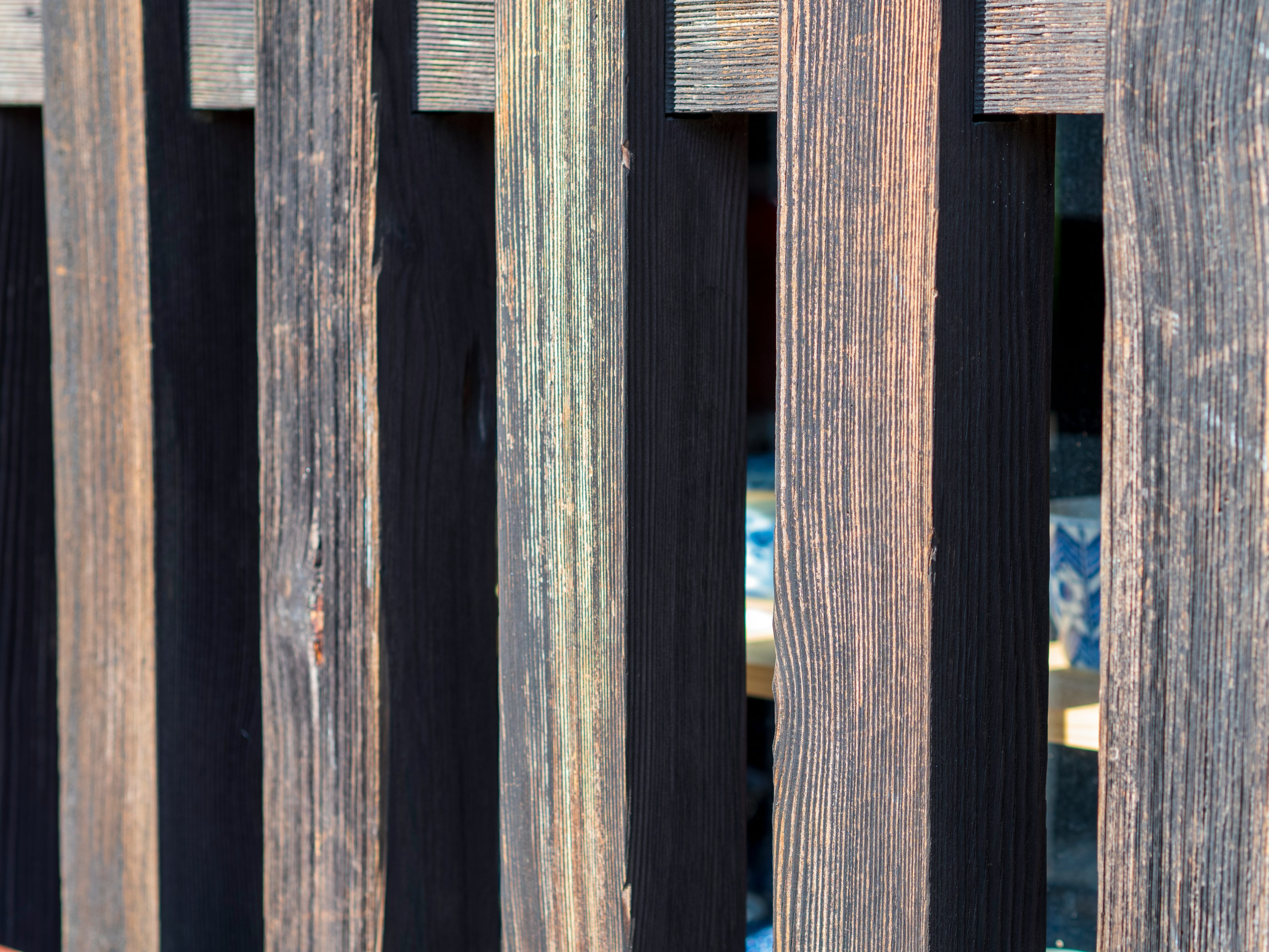 Wooden fence with gaps revealing blue pottery behind