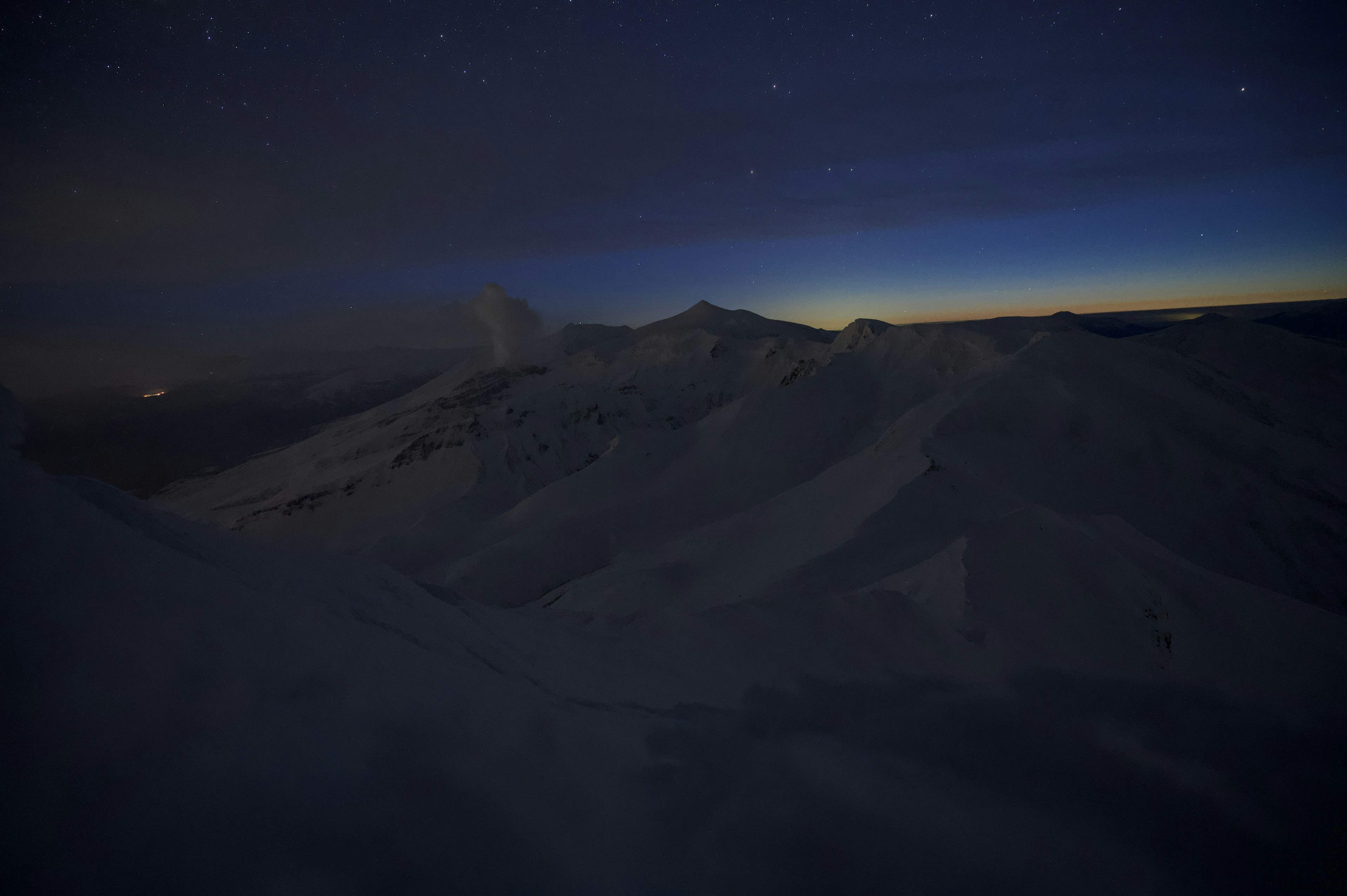 Silhouette di montagne sotto un cielo notturno con stelle