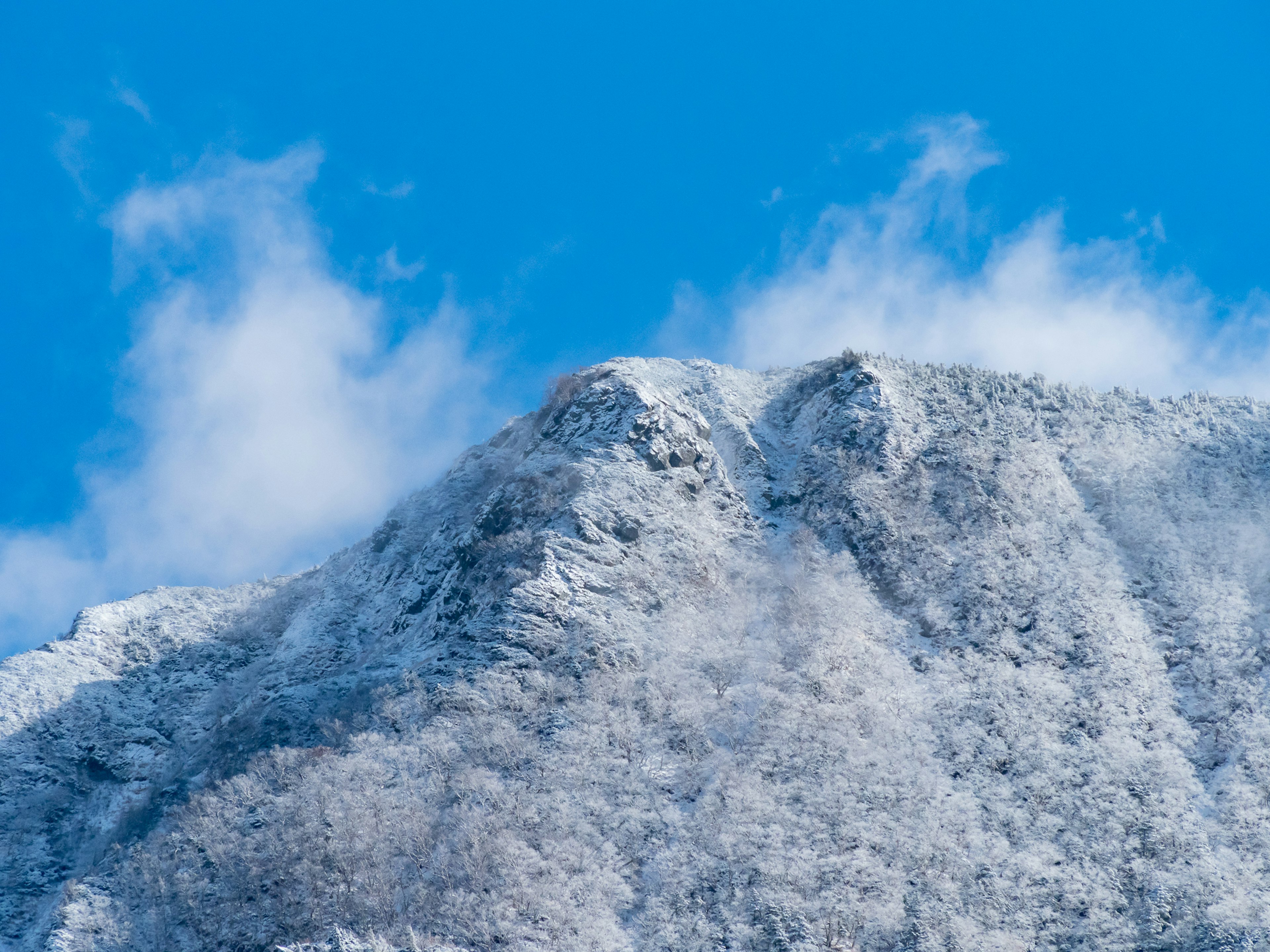 Schneebedeckter Berggipfel vor klarem blauen Himmel