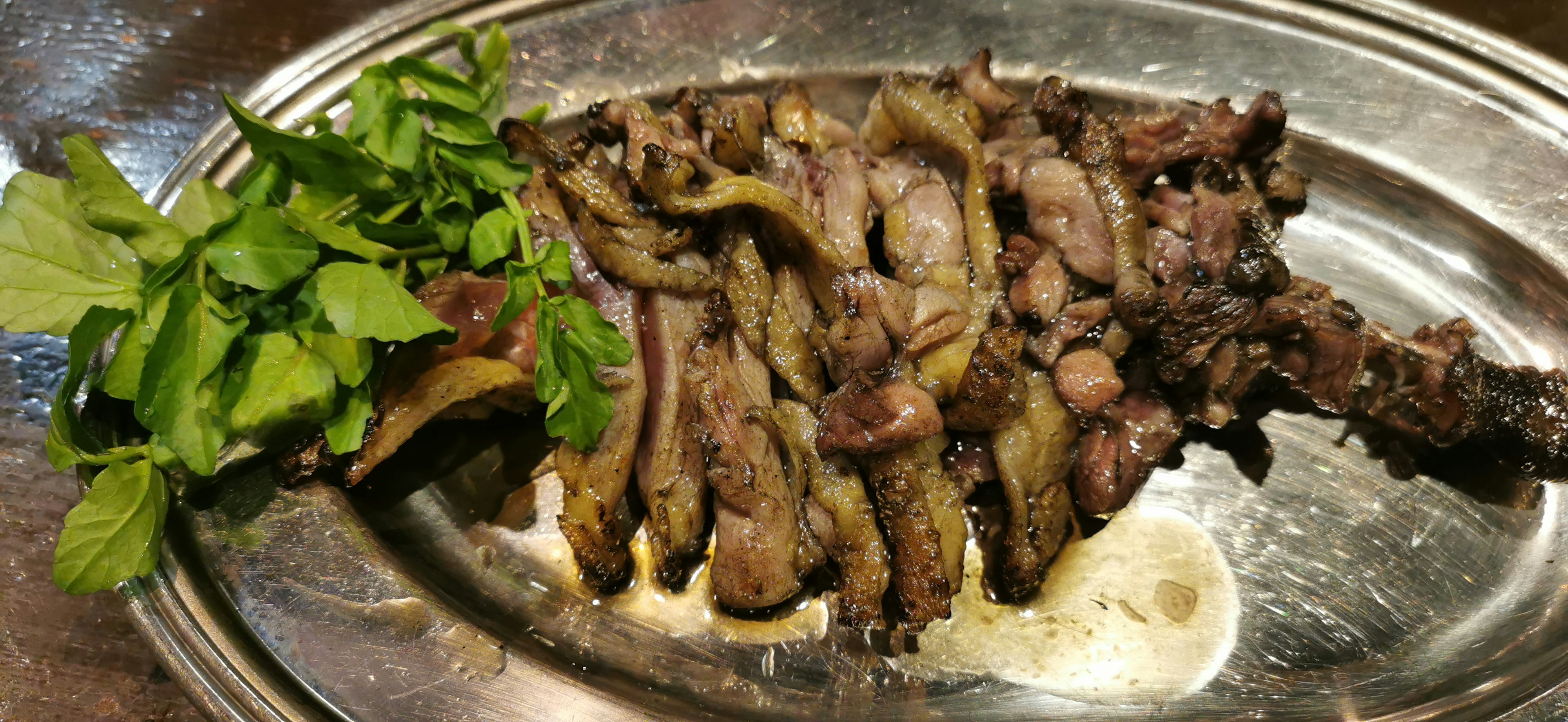 Viande grillée sur un plateau argenté avec des herbes fraîches